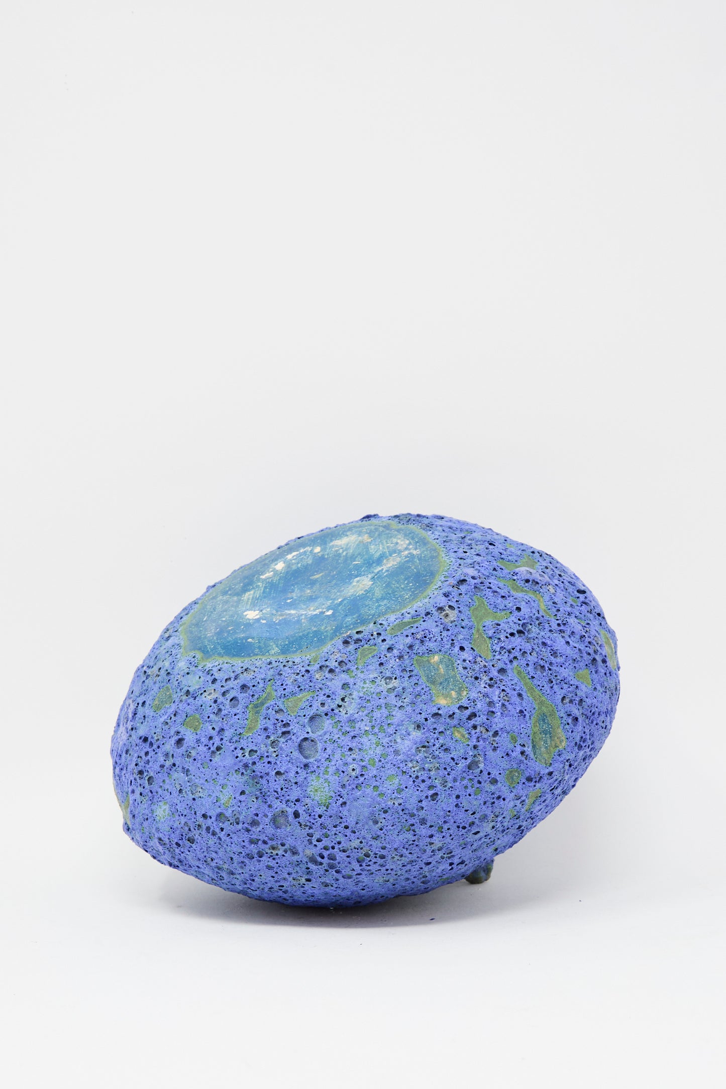 The MONDAYS Glazed Stoneware Moon Vase in Blue features a round, porous design with a lava blue and purple glaze, shiny translucent center, and is displayed against a plain white background.