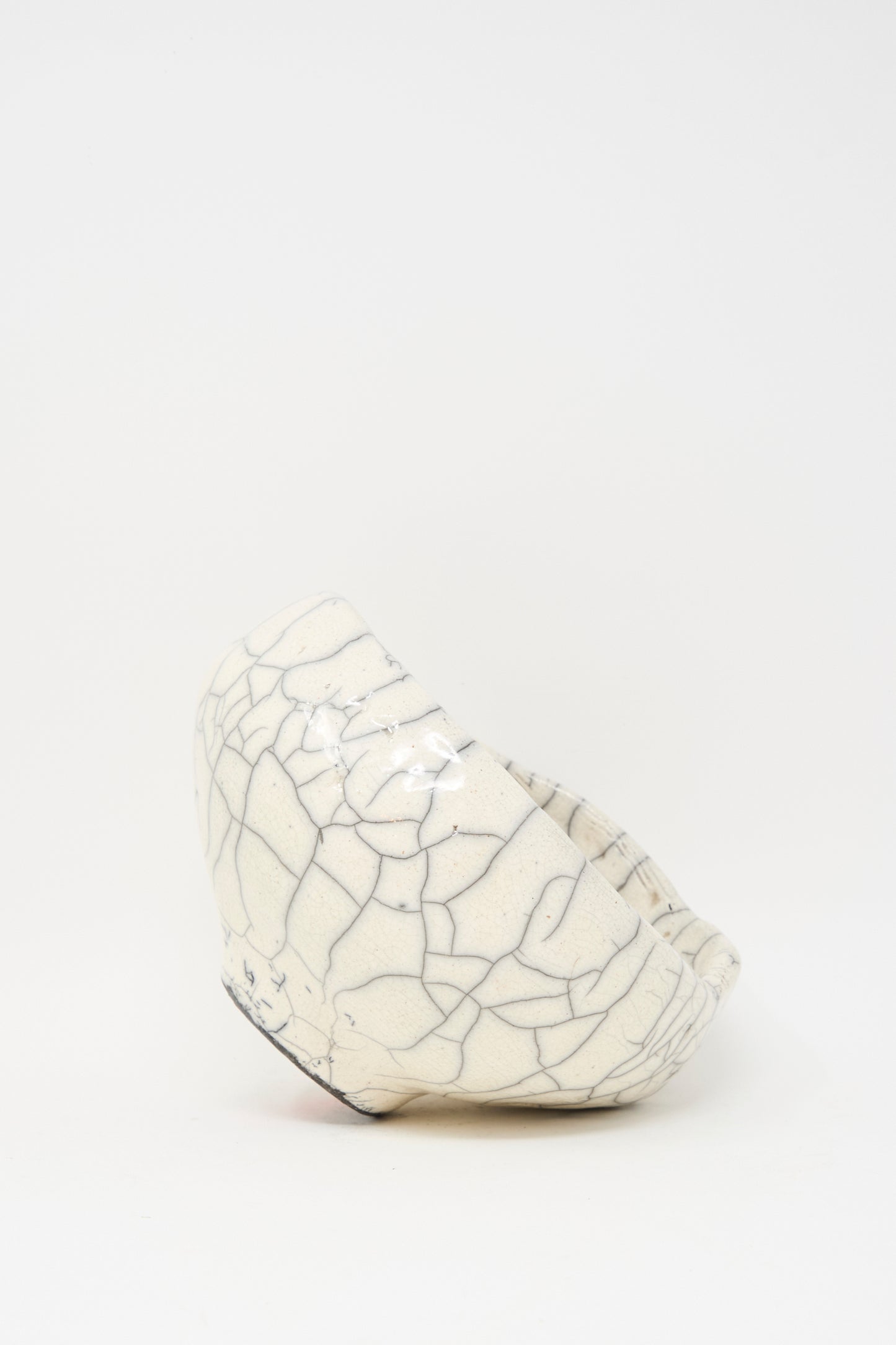 The MONDAYS Raku Coiled Bowl, crafted from white ceramic stoneware with a crackle glaze and raku-fired finish, is displayed on its side against a plain white background.