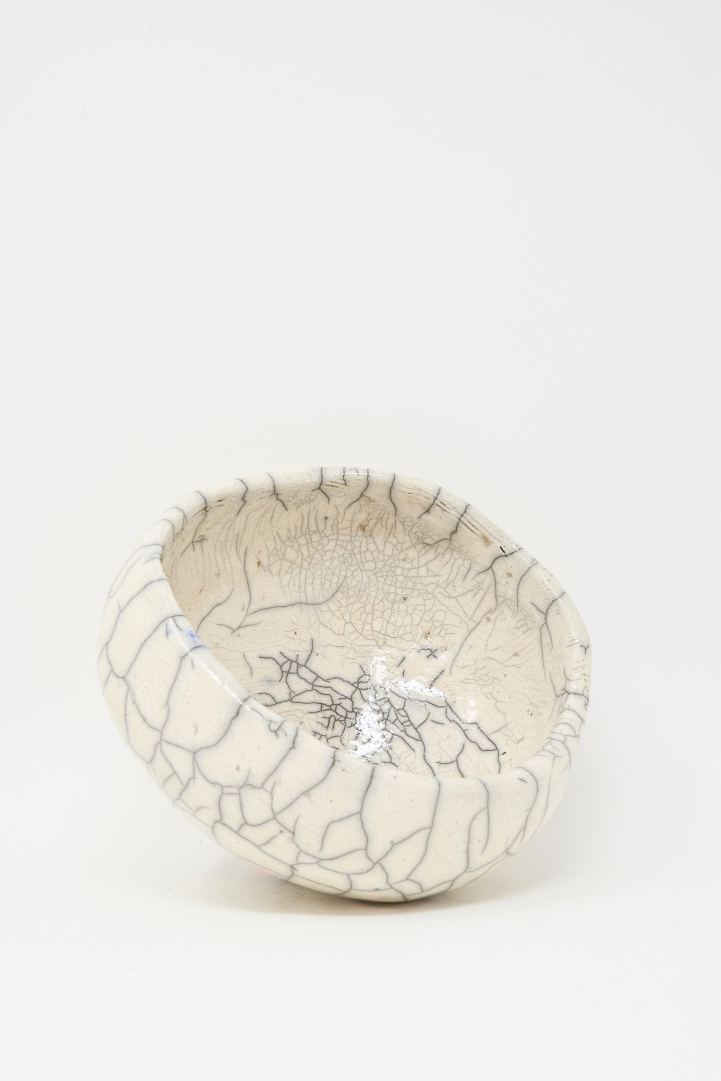 The MONDAYS Raku Coiled Bowl is a white ceramic piece with an uneven rim and unique crackle glaze, crafted from raku-fired stoneware, shown against a plain white background.