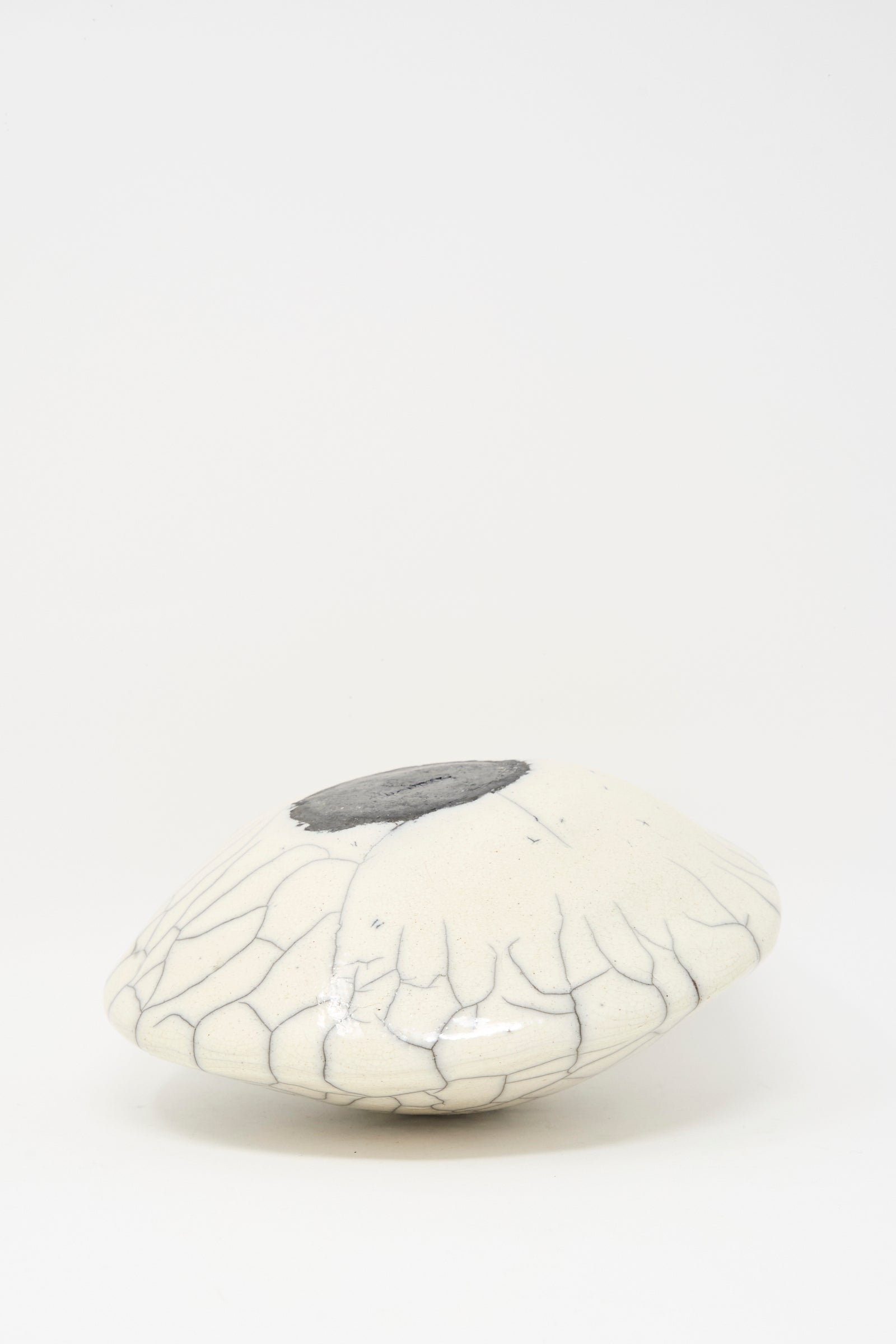 The MONDAYS Raku Ikebana Vase Large is a smooth, white, dome-shaped stoneware piece with fine black crackle glaze lines and a dark circular spot on top, shown against a plain white background.