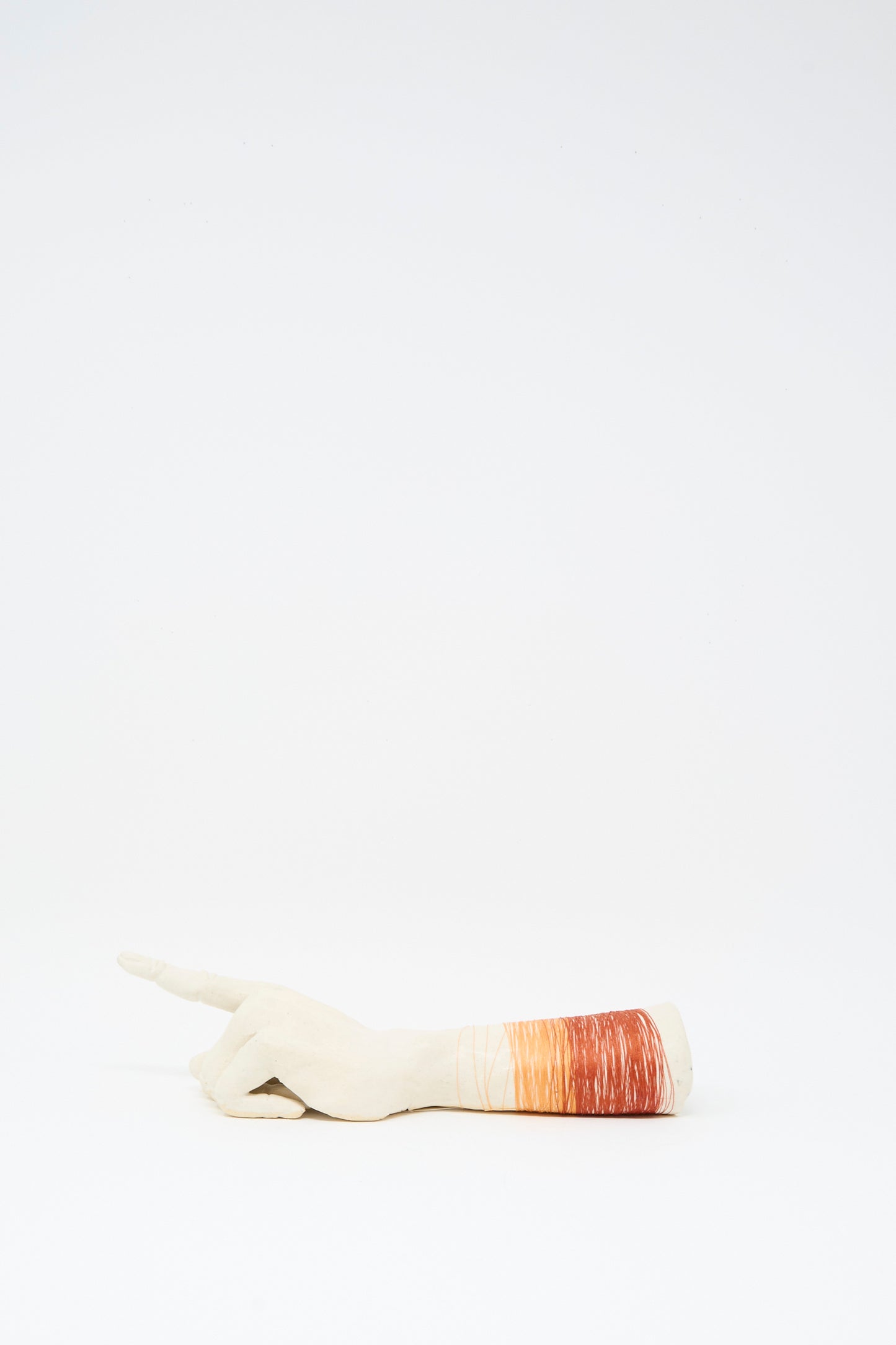 The Monty J Ceramic Hand Sculpture with Orange and Red Thread rests on its side against a plain white background, showcasing handcrafted Brooklyn artistry.