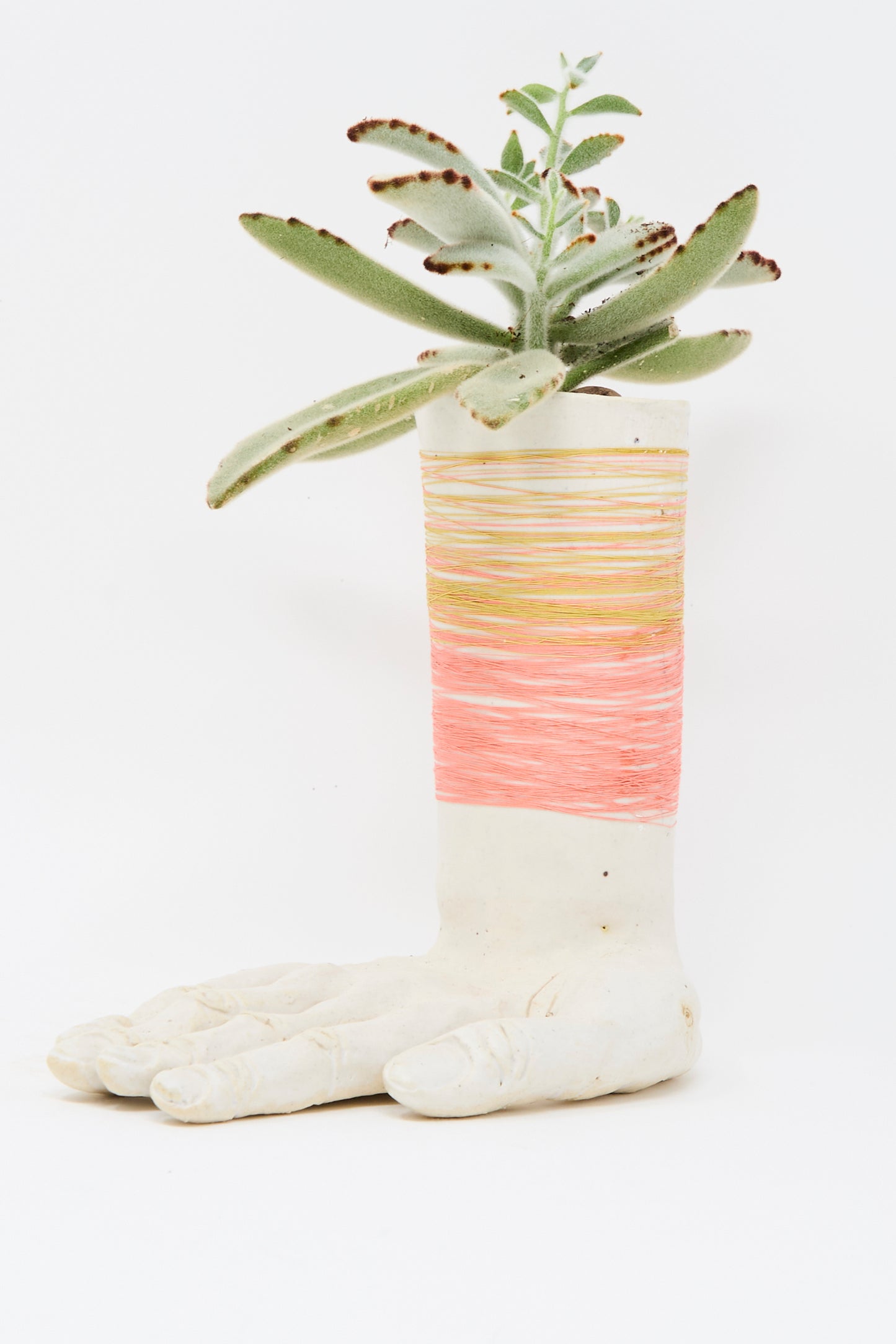 The Monty J Ceramic Hand Sculpture with Pink and Gold Thread is a handmade Brooklyn piece, shaped like a hand and wrapped in pink and gold thread.