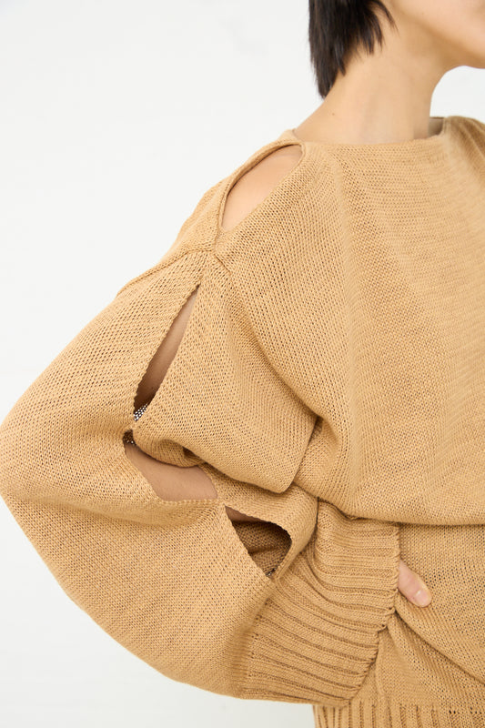 A woman wearing an oversized Niccolò Pasqualetti Cotton Linen Yarn Sfogo Sweater in Golden Beige with a boat neck.