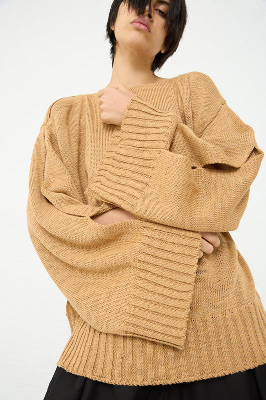 An oversized Niccolò Pasqualetti Camel Sweater with boat neck, paired with black pants. Front view.