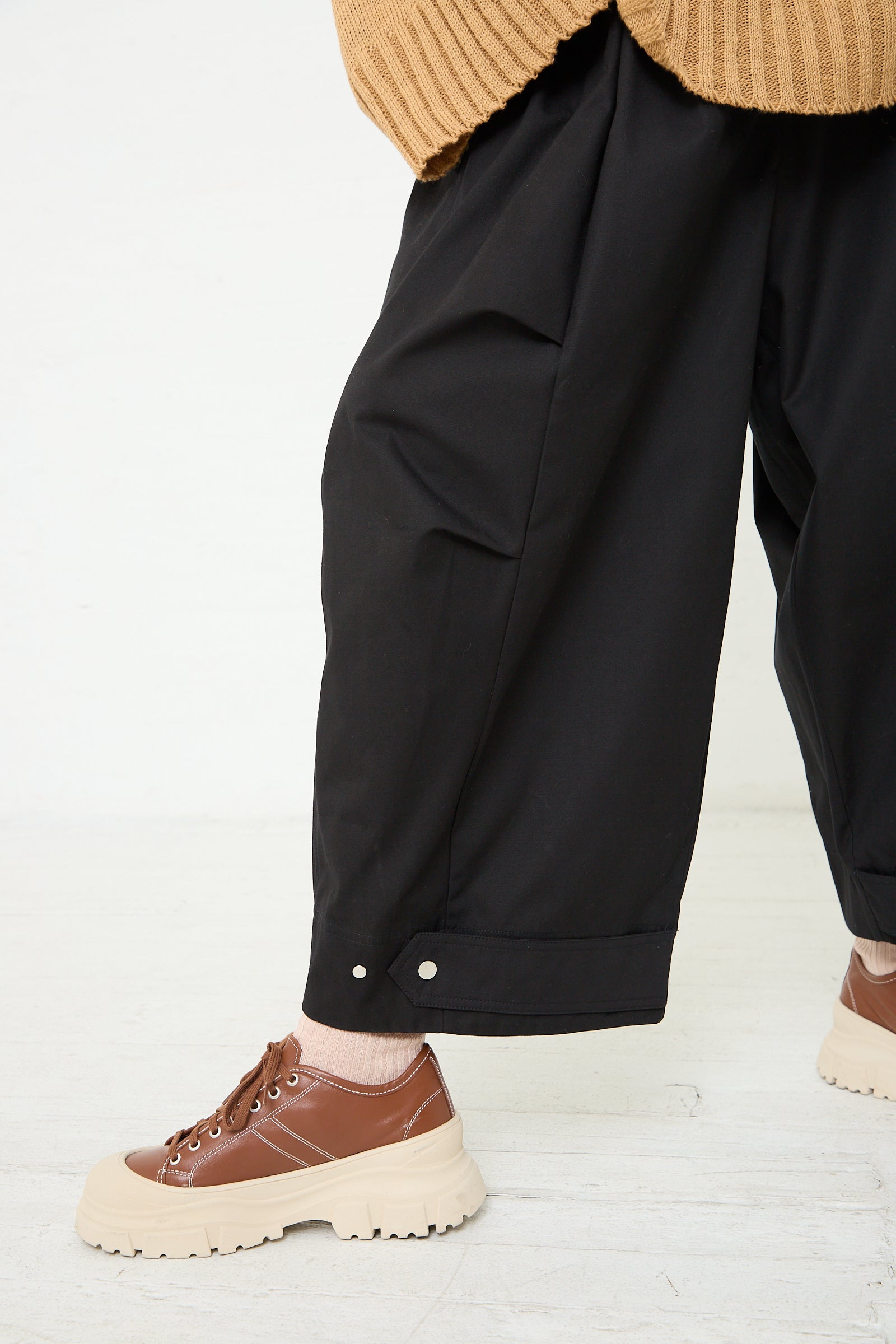 A woman wearing the Niccolò Pasqualetti Cotton Twill Luna Trouser in Black and a tan sweater. Up close view of pant.