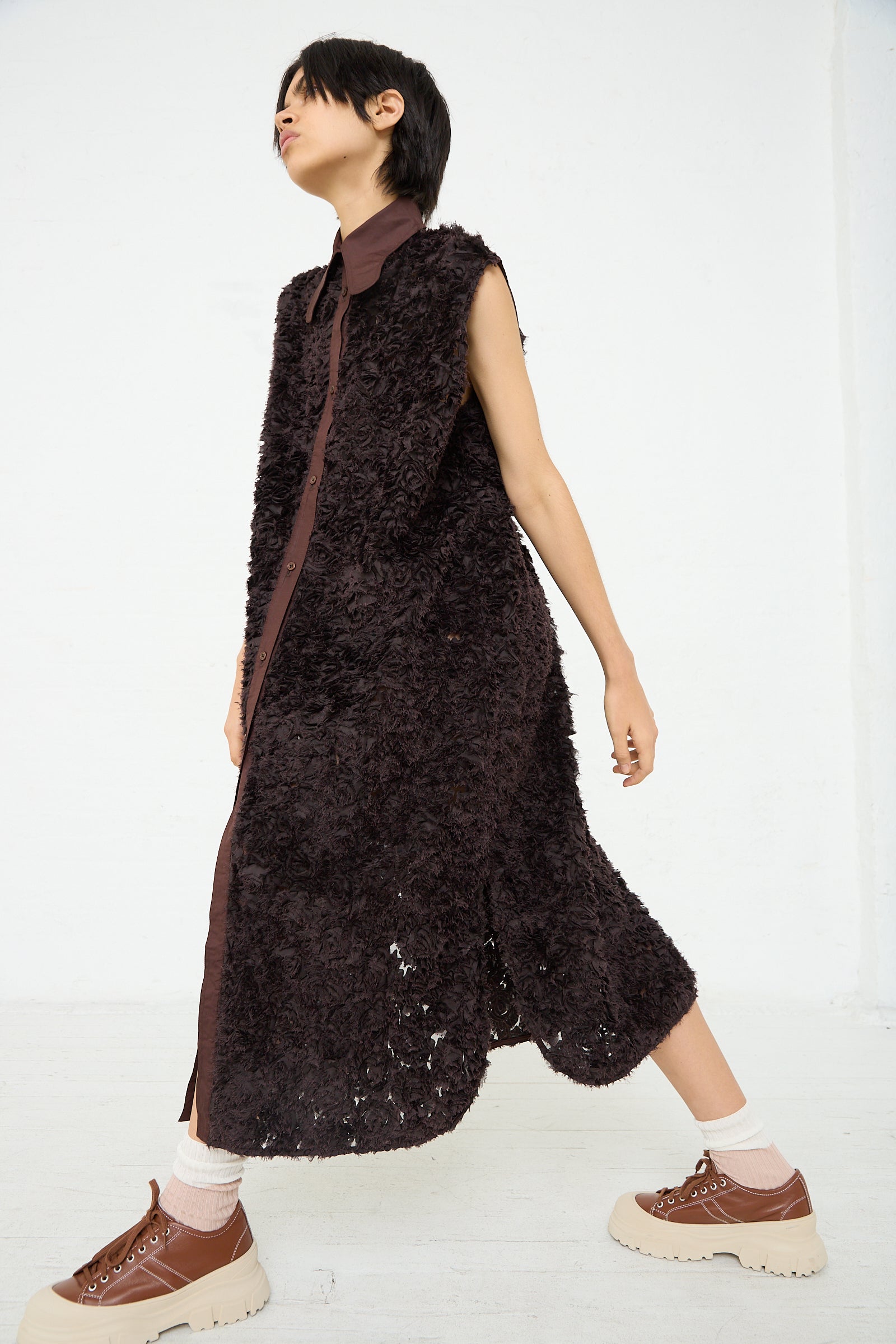 A woman is wearing an intricately embroidered Niccolò Pasqualetti Beagle Shirt Dress in Dark Brown.