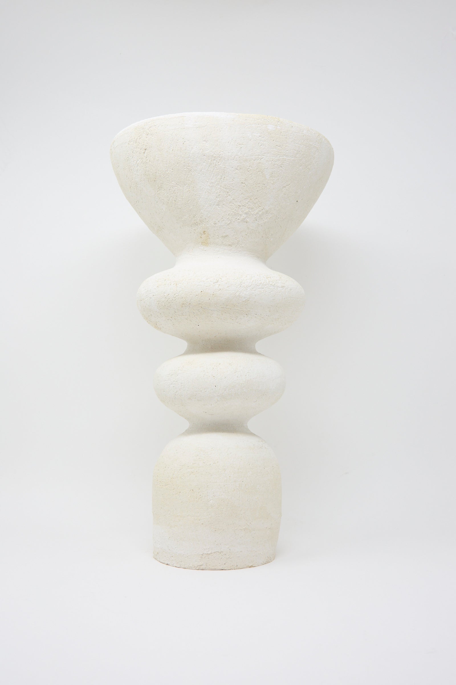 Introducing the Monolith Vessel by Oatmeal, a sculptural ceramic piece handmade in Pennsylvania. This vessel features a textured surface with a wide top and multiple rounded, stacked forms in white, against a plain background.