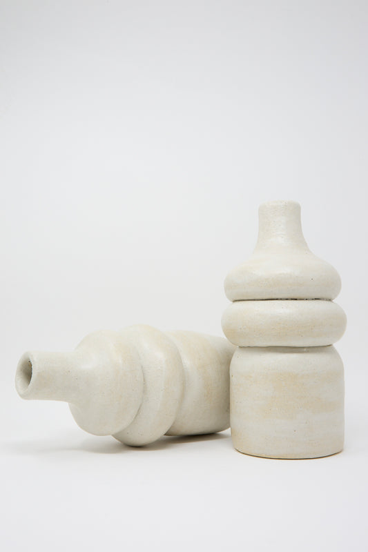 Displayed against a plain background, two Prune Vessels by Oatmeal are showcased—one positioned upright while the other rests horizontally.