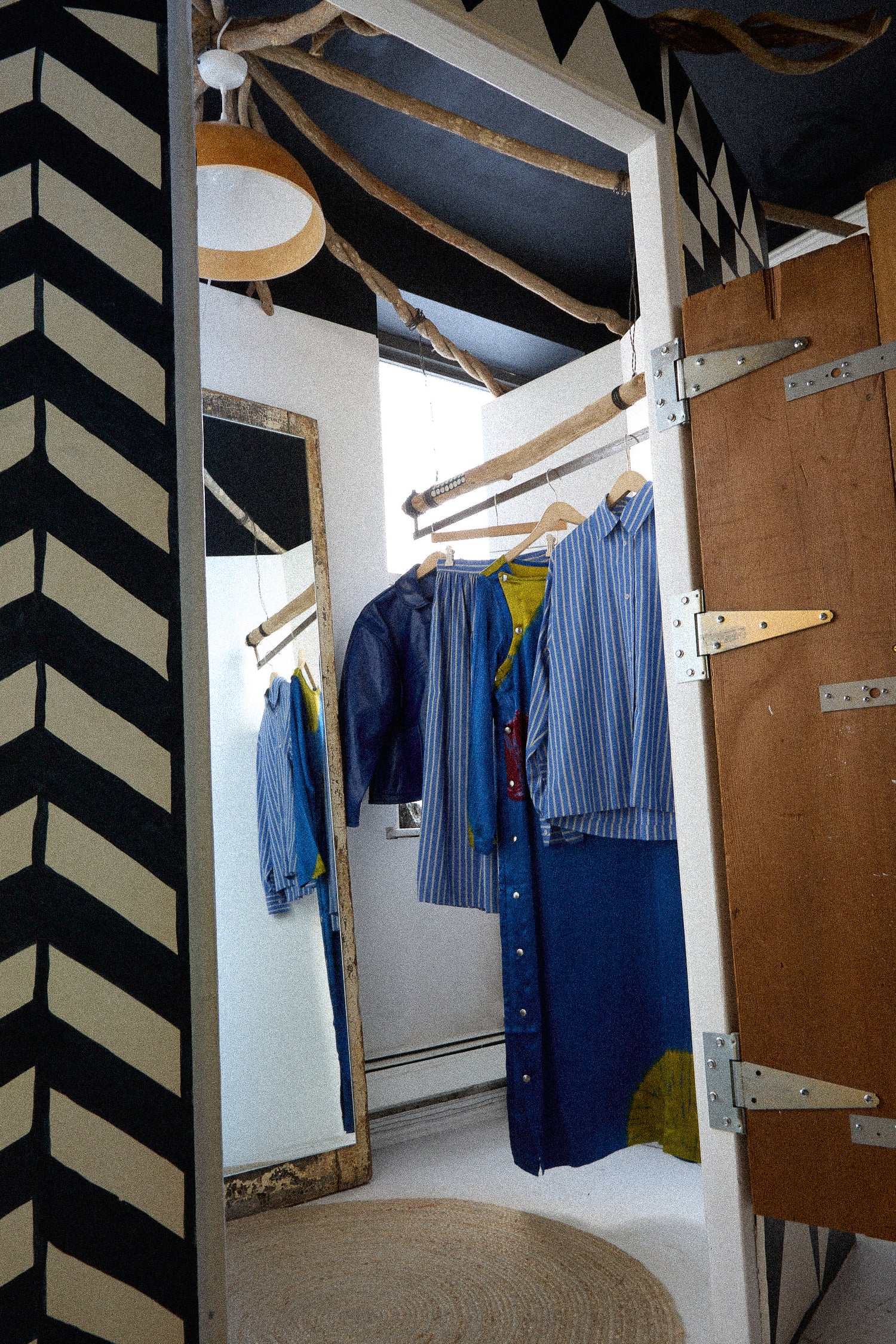 Clothing hanging on a rack with a black and white zigzag pattern on the wall.