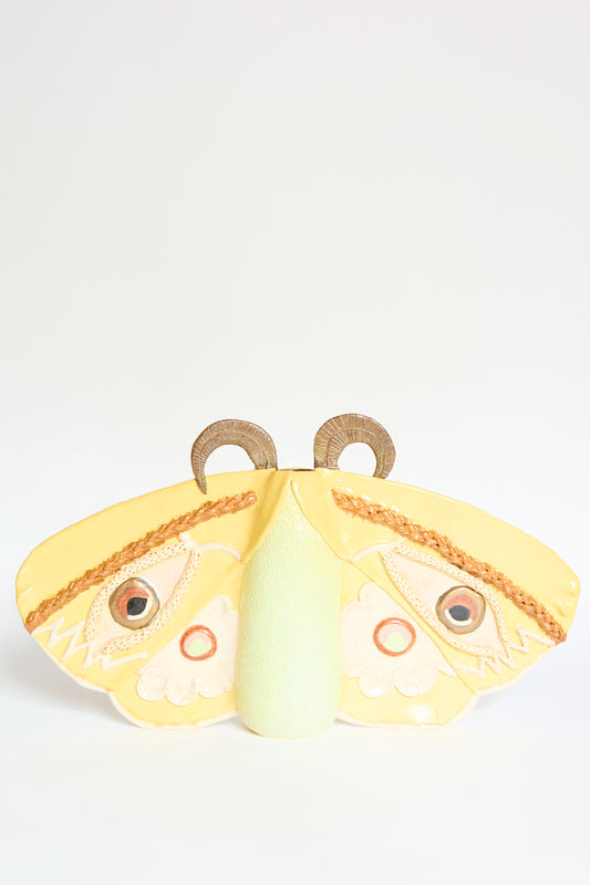 The Emperor Moth in Yellow by Pearce Williams is a handmade stoneware vase featuring decorative patterns and two circular shapes on top, displayed against a plain white background.