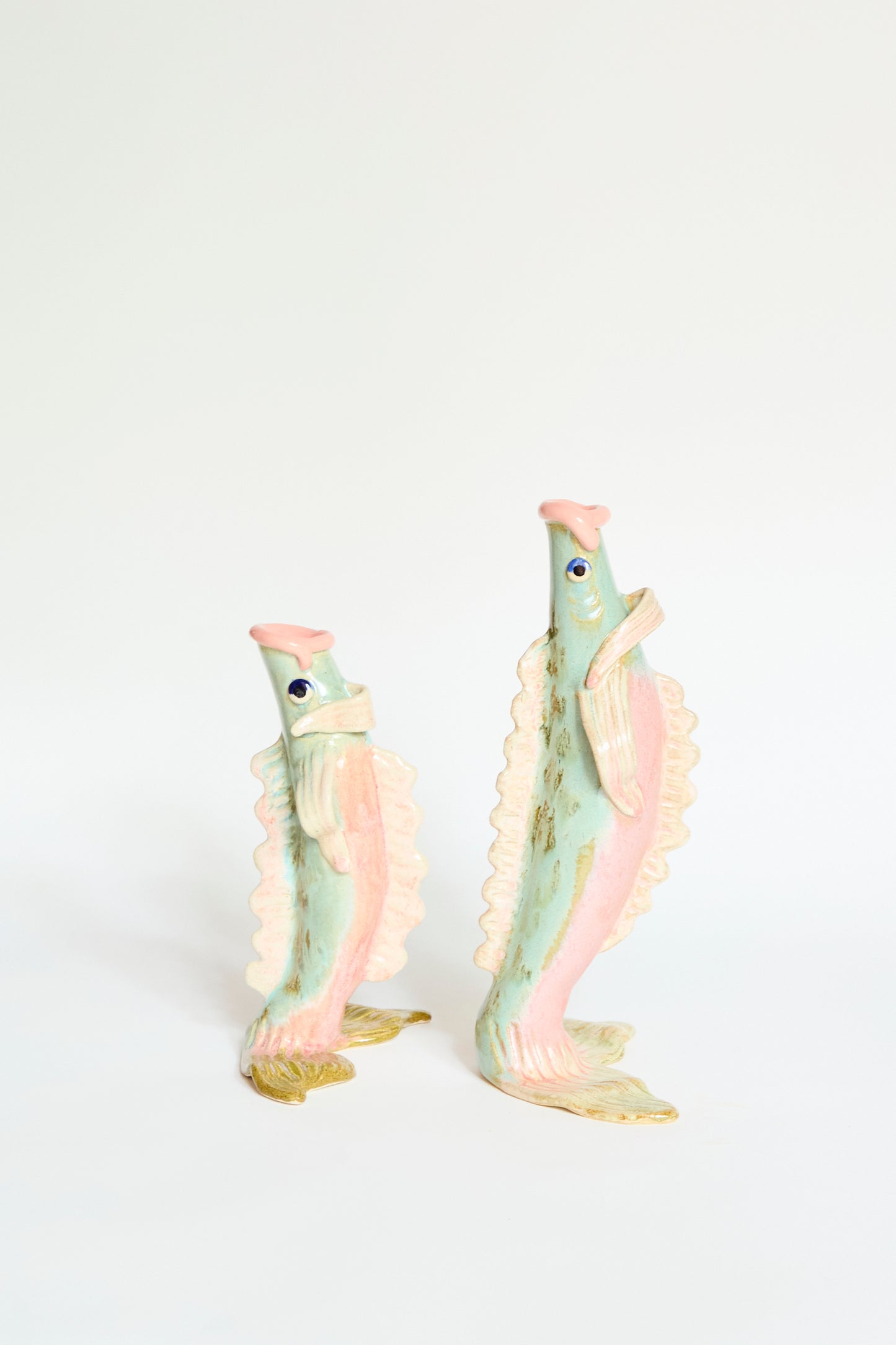 The Pearce Williams Fish Vase Large in Green is a handmade stoneware figurine with pastel green and yellow hues, standing upright on a plain white background.