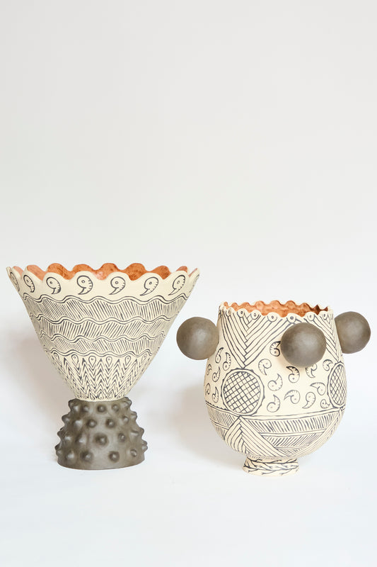 The Pearce Williams Patterned Cone Vase features handcrafted ceramic with intricate black patterns on white; each unique vase showcases artisanal details and distinctive shapes, making them elegant statement pieces.