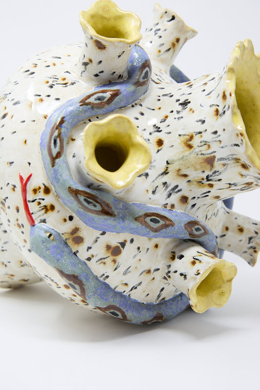 A speckled, abstract glazed stoneware sculpture with multiple swirling openings and protrusions in shades of blue, yellow, and red by Pearce Williams called the Snake Tulipiere.