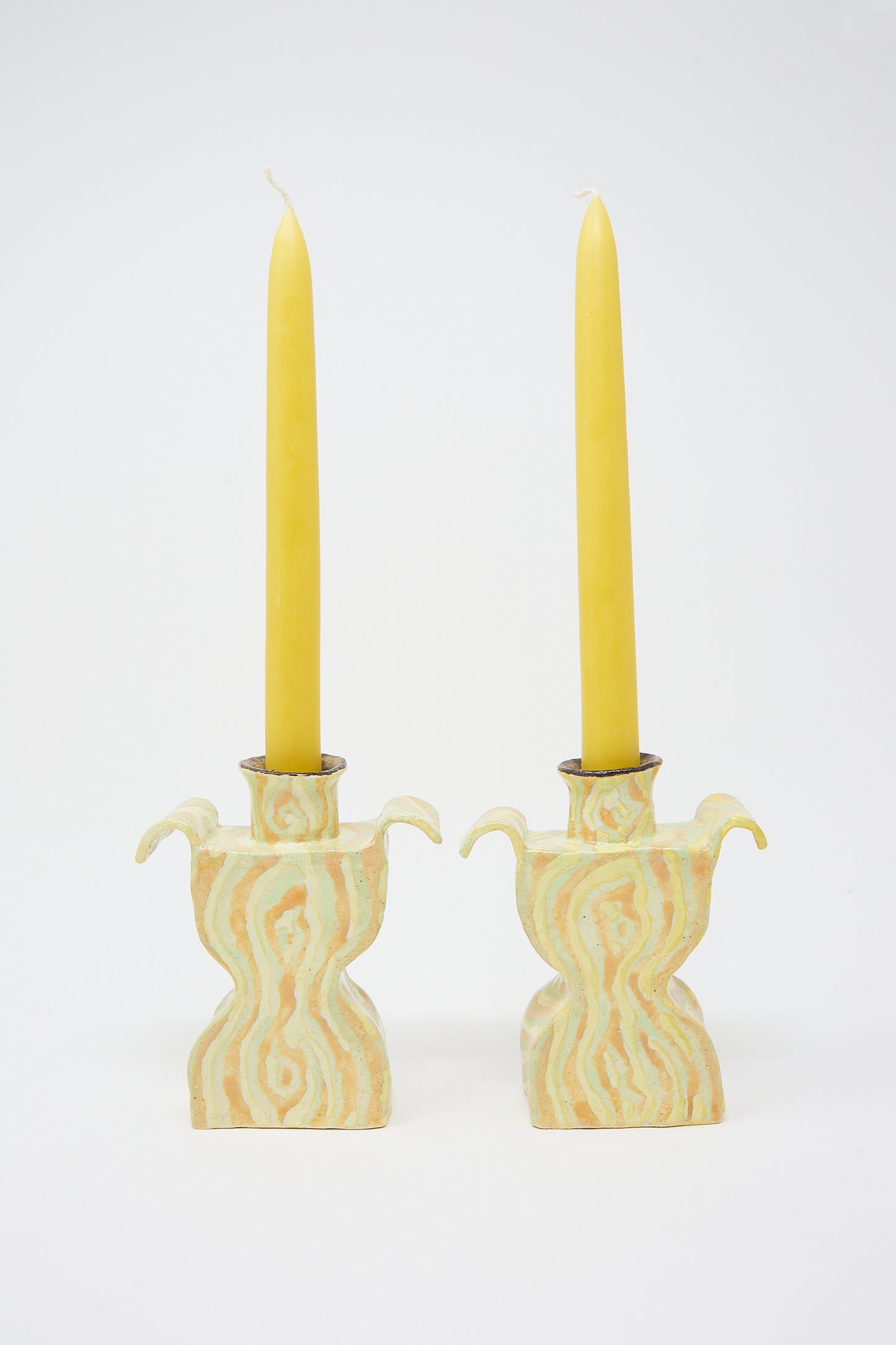 Two Woodgrain Candlesticks Pair standing in ornate, handcrafted ceramic candle holders against a white background. (Brand Name: Pearce Williams)