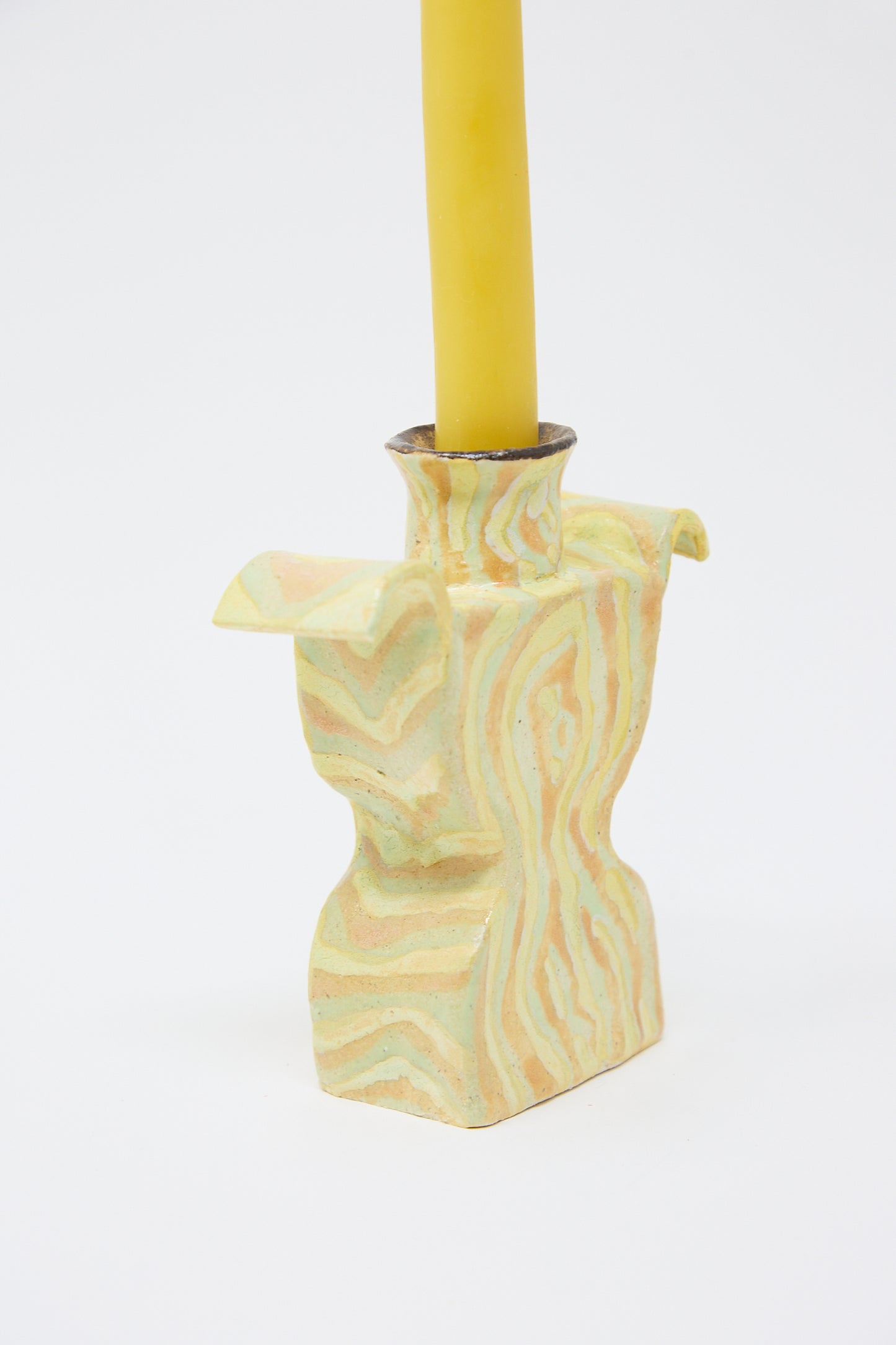 A Pearce Williams Woodgrain Candlesticks Pair positioned in a marbled, multicolored handcrafted ceramic candle holder with an abstract design on a white background.