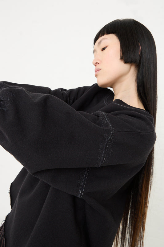 A person with long black hair wearing a Rachel Comey Fond Sweatshirt in Charcoal standing against a white background.