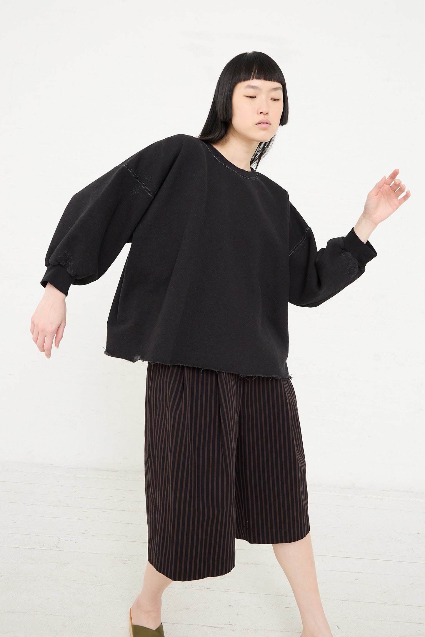 Woman in Rachel Comey's Fond Sweatshirt in Charcoal and striped shorts posing against a white background.