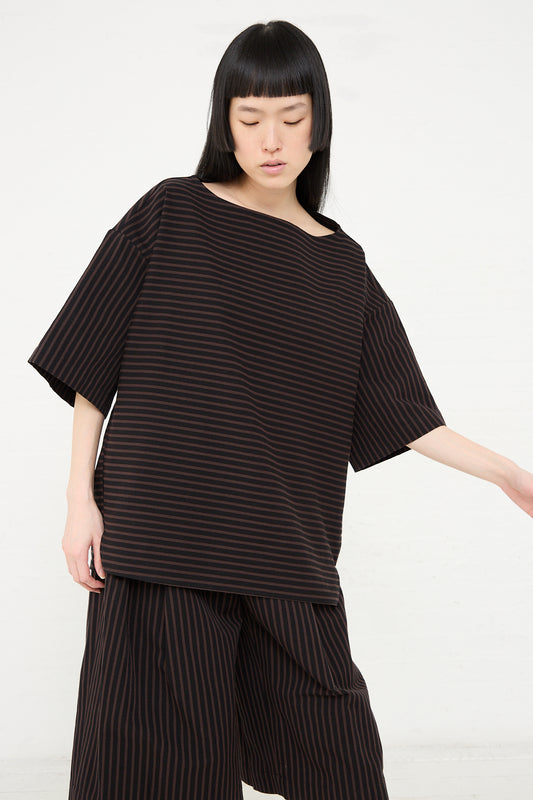 A woman wearing a Rachel Comey Ode Top in Black with a boatneck collar and matching pants stands against a white background.