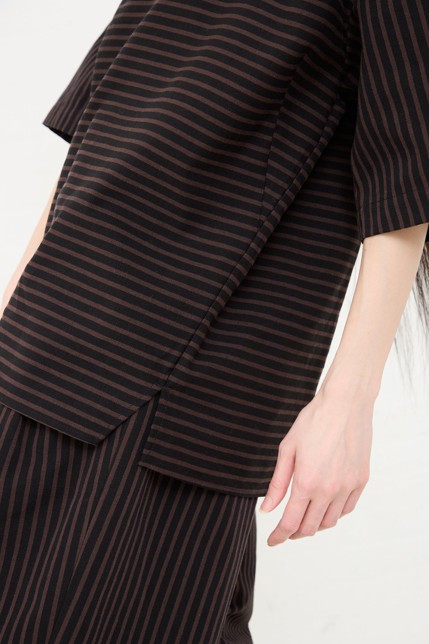 A close-up of a person wearing a Rachel Comey Ode Top in Black with a focus on the fabric's texture and boatneck collar pattern.