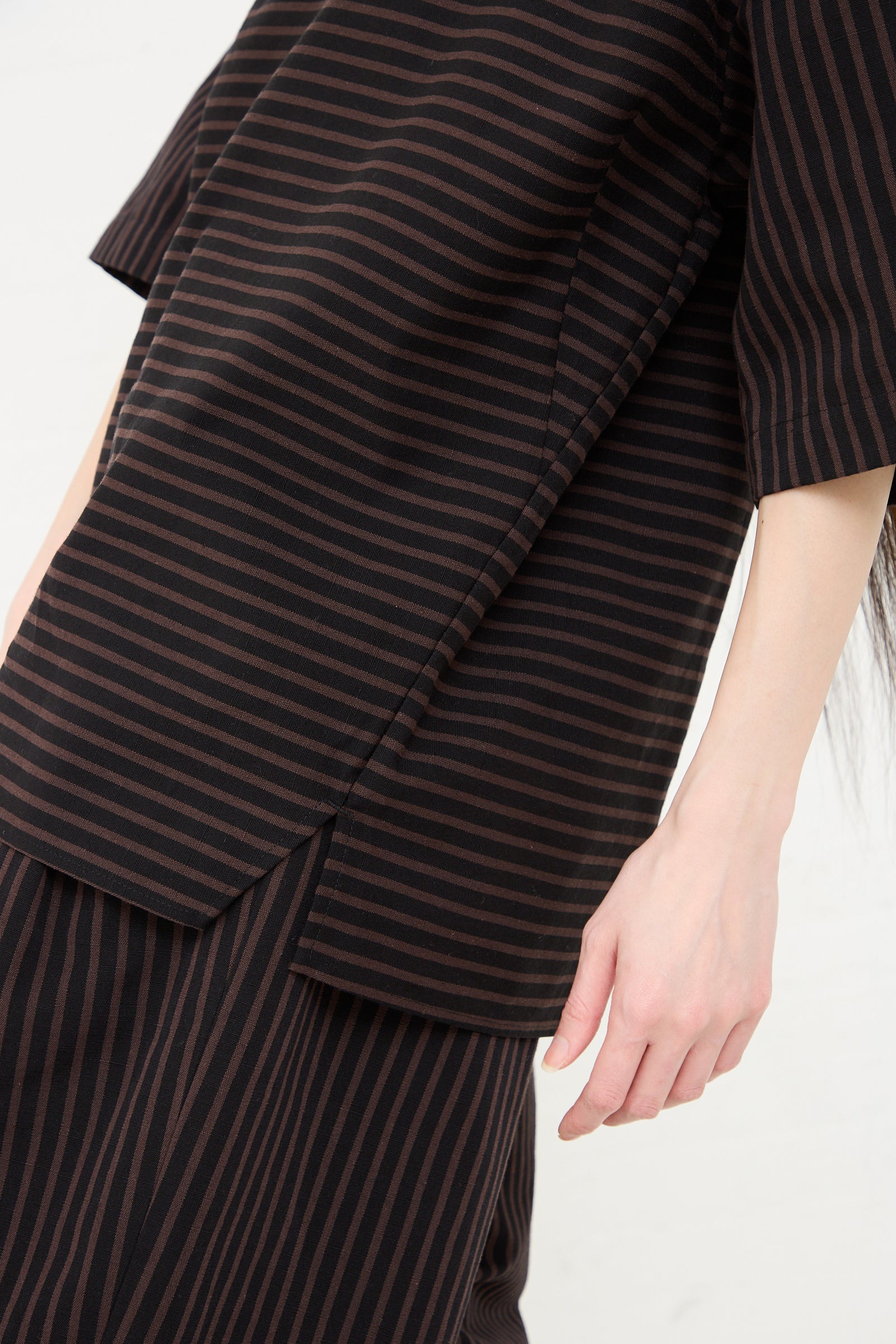 A close-up of a person wearing a Rachel Comey Ode Top in Black with a focus on the fabric's texture and boatneck collar pattern.
