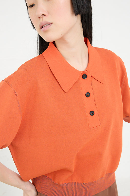 Woman wearing a modern Rachel Comey Omin Top in Orange with a collar and buttons.