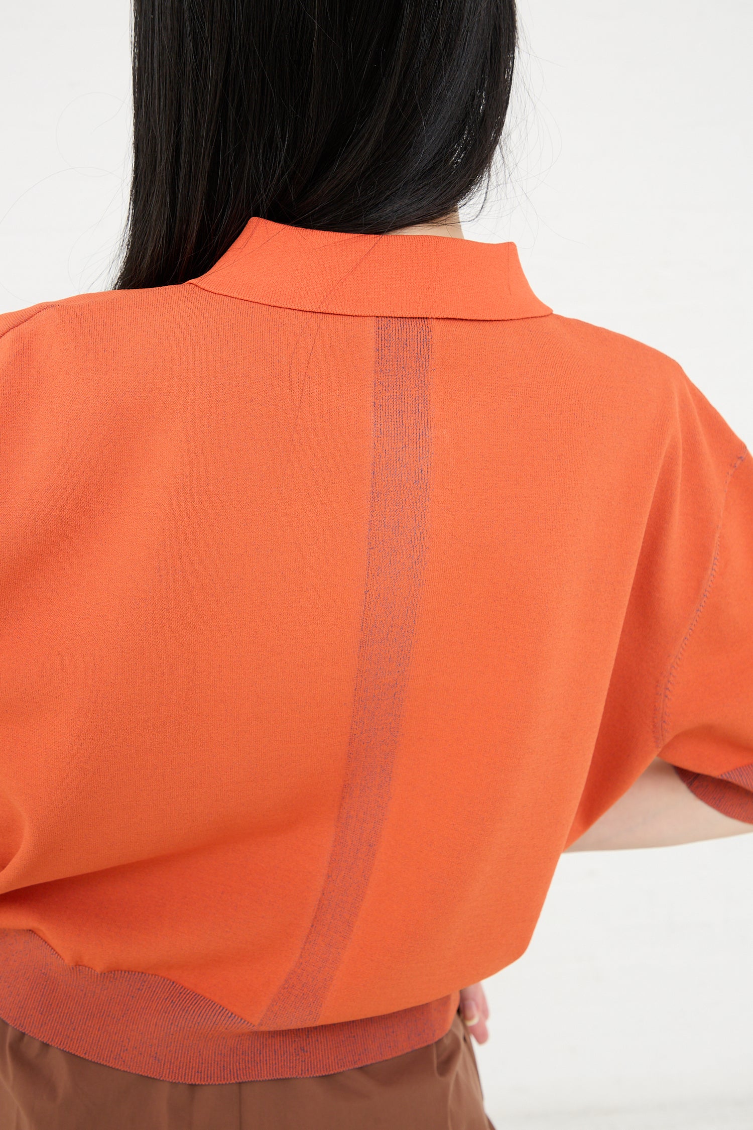 A person seen from behind wearing an Omin Top in Orange by Rachel Comey with a vertical seam detail.