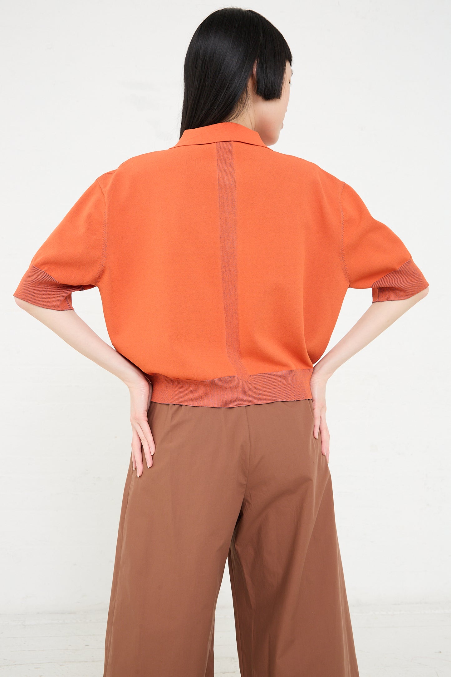 A woman seen from the back wearing a Rachel Comey Omin Top in Orange and brown trousers.