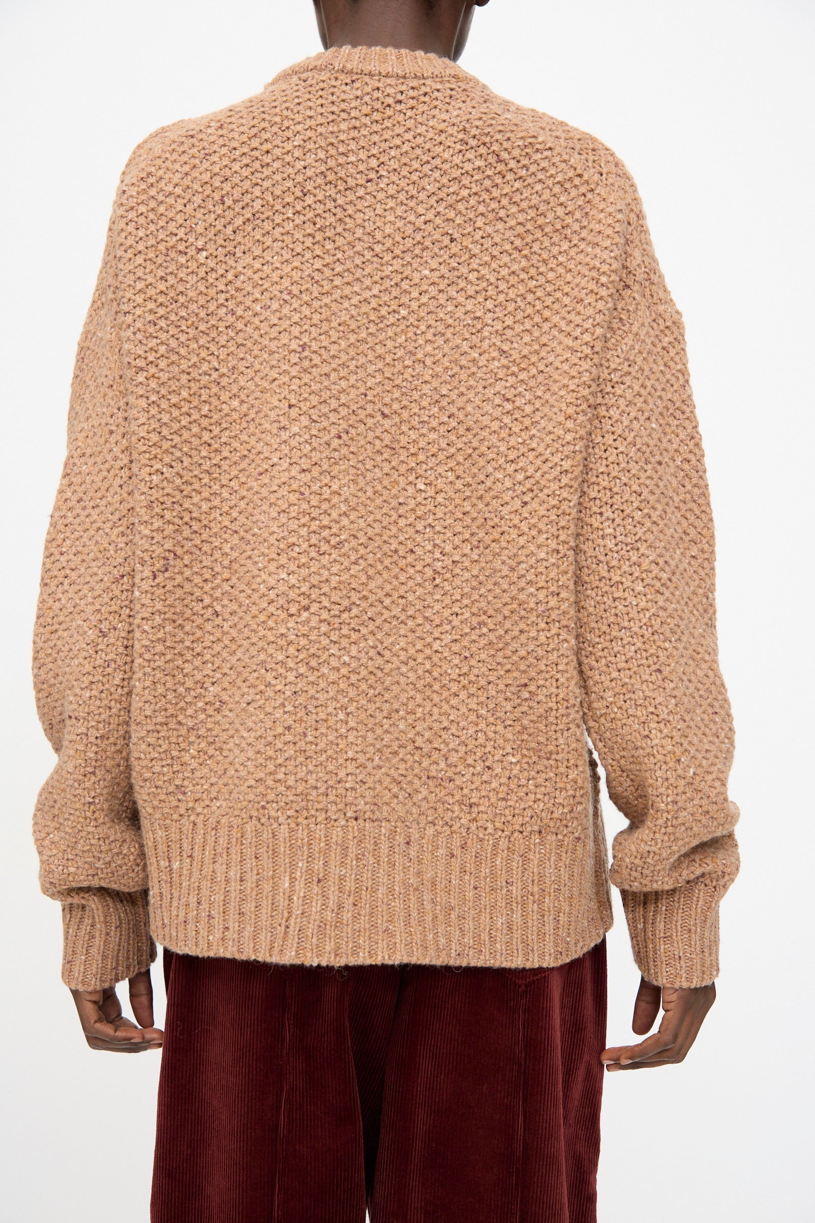 Model wears the Prescot Sweater in Caramel by Rachel Comey, a heavyweight knit long sleeve, paired with red corduroy pants. Shown from the back against a plain light background.