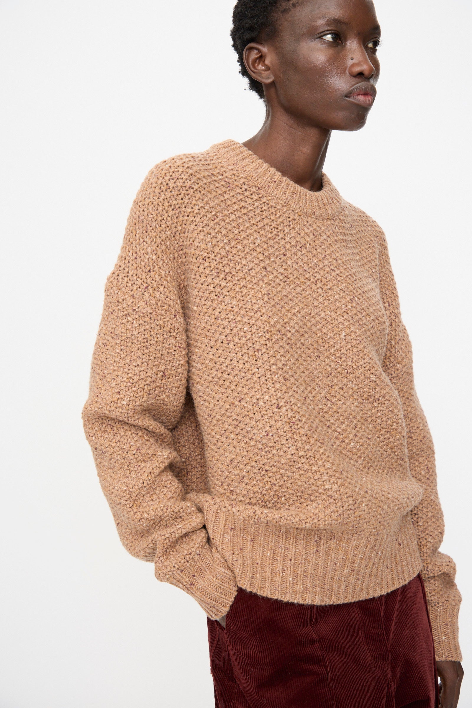 A person wearing the Rachel Comey Prescot Sweater in Caramel stands against a plain white background.