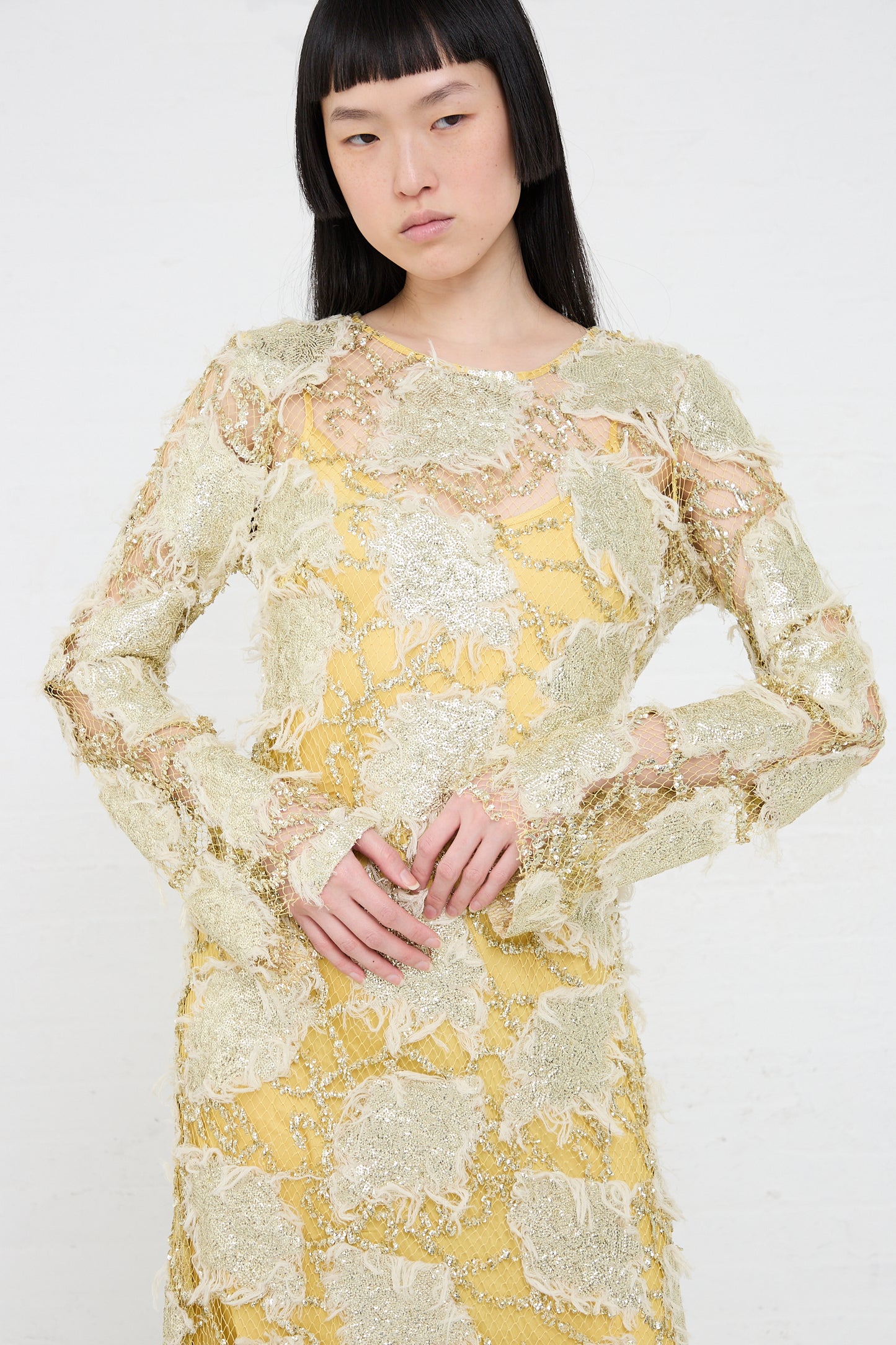 Woman posing in a Rachel Comey Silla Dress in Gold with hands gently clasped in front.
