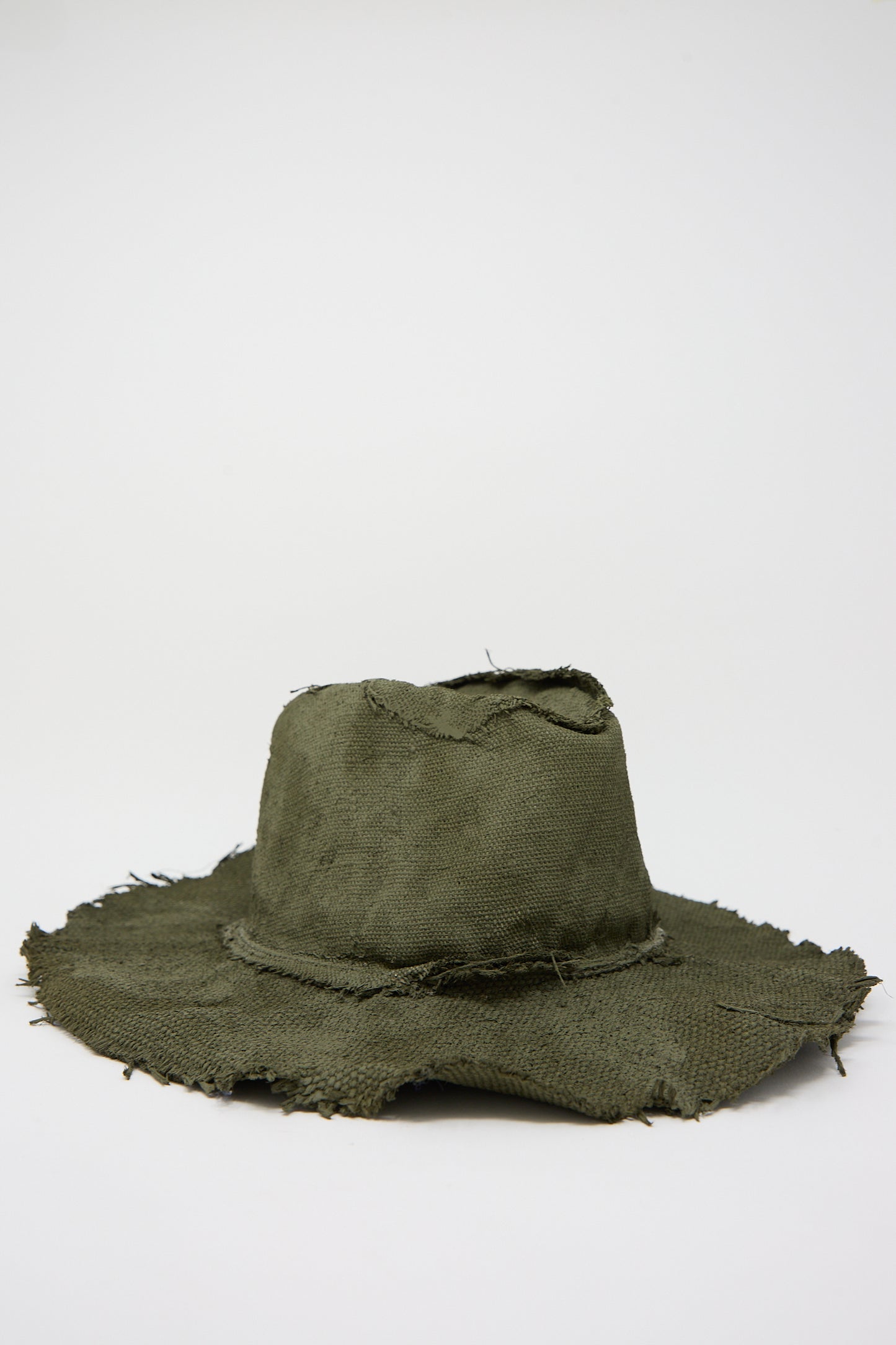 A worn, frayed Reinhard Plank Beghe S Jute Hat in Green with visible stitching and holes, displayed against a plain white background.
