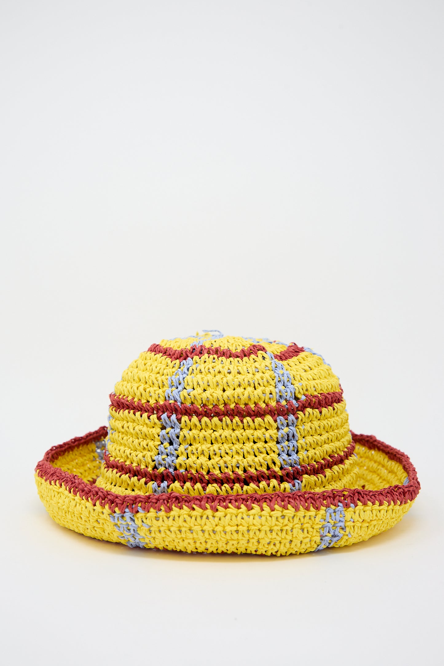 A colorful crocheted hat in yellow, red, and blue on a white background, designed by Reinhard Plank.