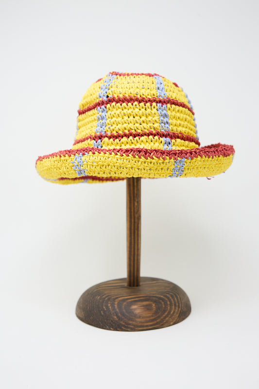 A colorful Artista Paper Unci hat in Yellow Lines by Reinhard Plank displayed on a wooden stand against a white background.