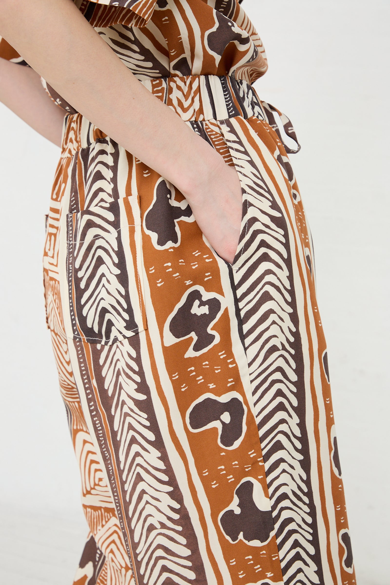 Woman wearing Rejina Pyo Andi Trouser in Print Brown with a vintage-inspired hand-painted print, hand in pocket.