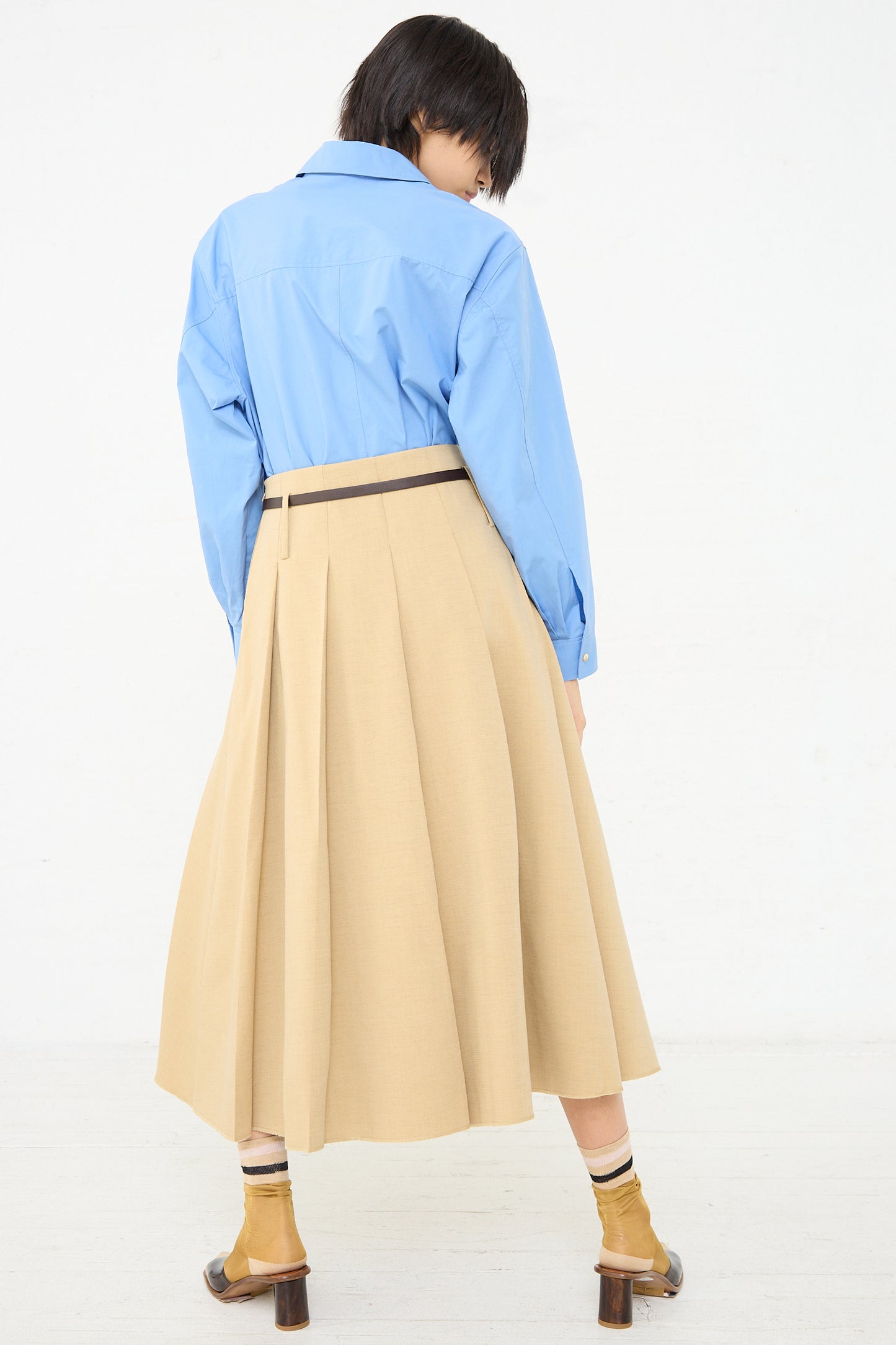 The back view of a woman wearing a Rejina Pyo Odette Skirt in Beige.