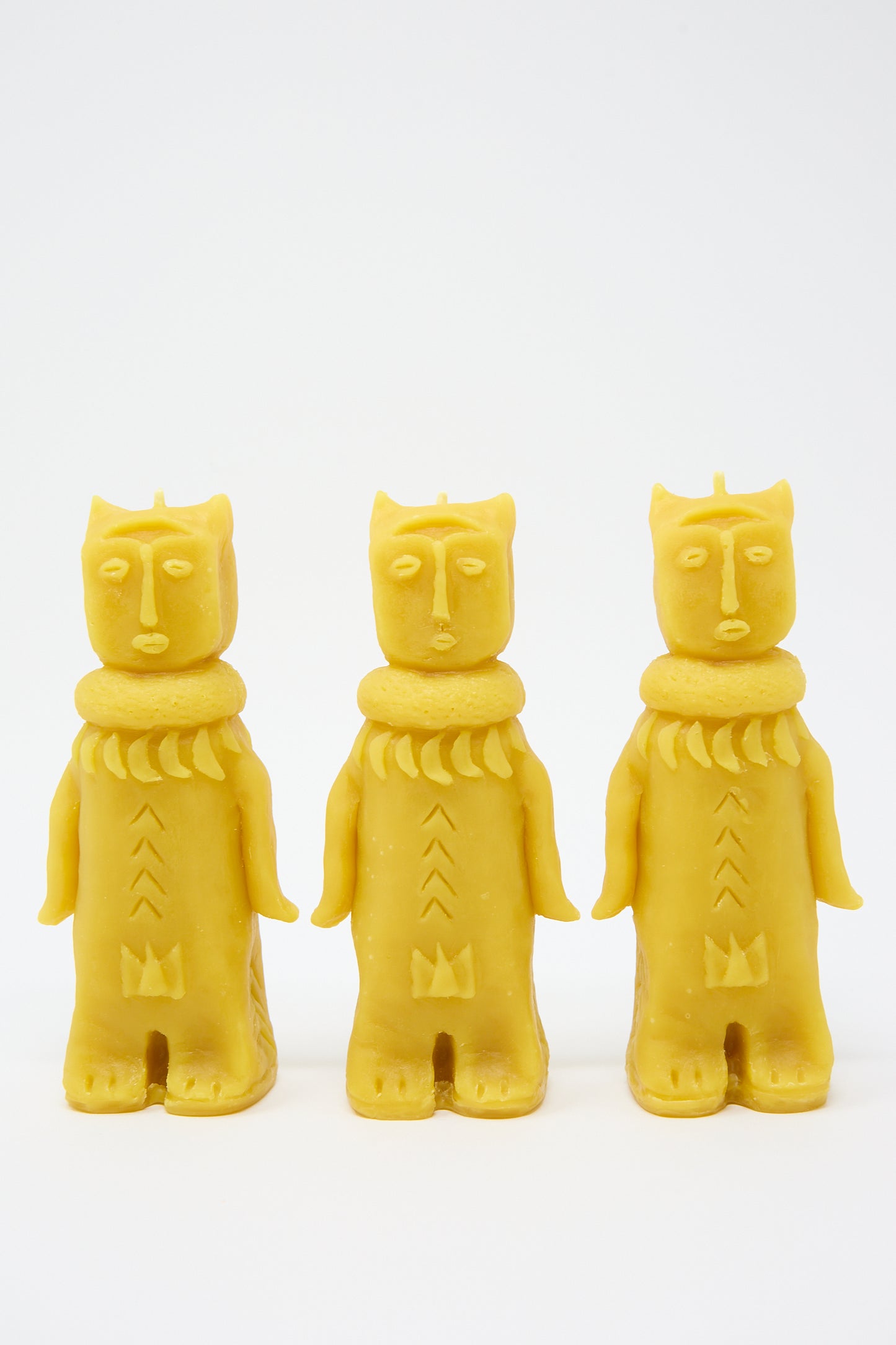 Three yellow Forest Goddess Candles by Rinn to Hitsuji shaped like cats wearing scarves, standing in a row, against a white background.