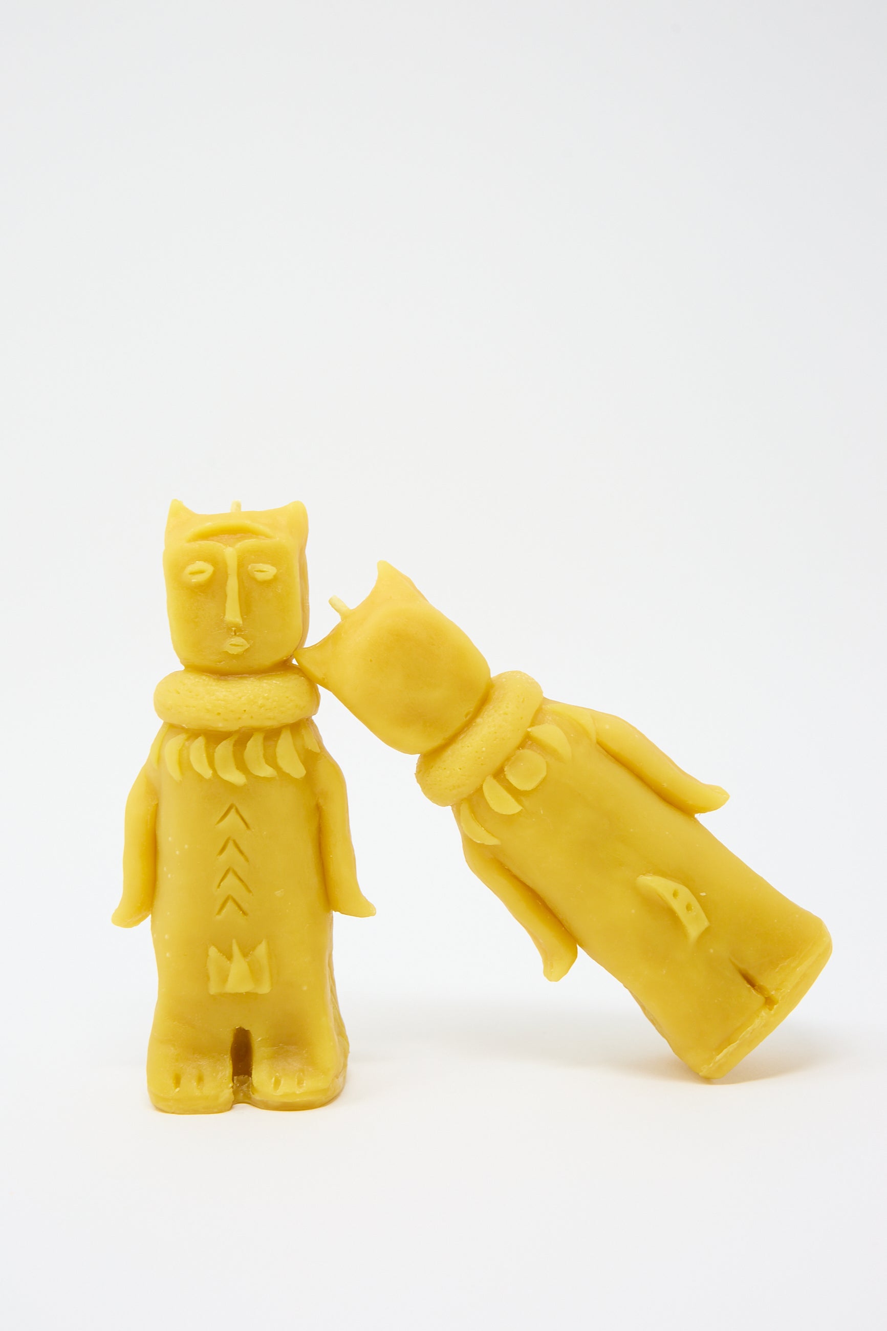 Two yellow Rinn to Hitsuji Forest Goddess Candles shaped like stylized human figures, standing upright and leaning towards each other against a white background.
