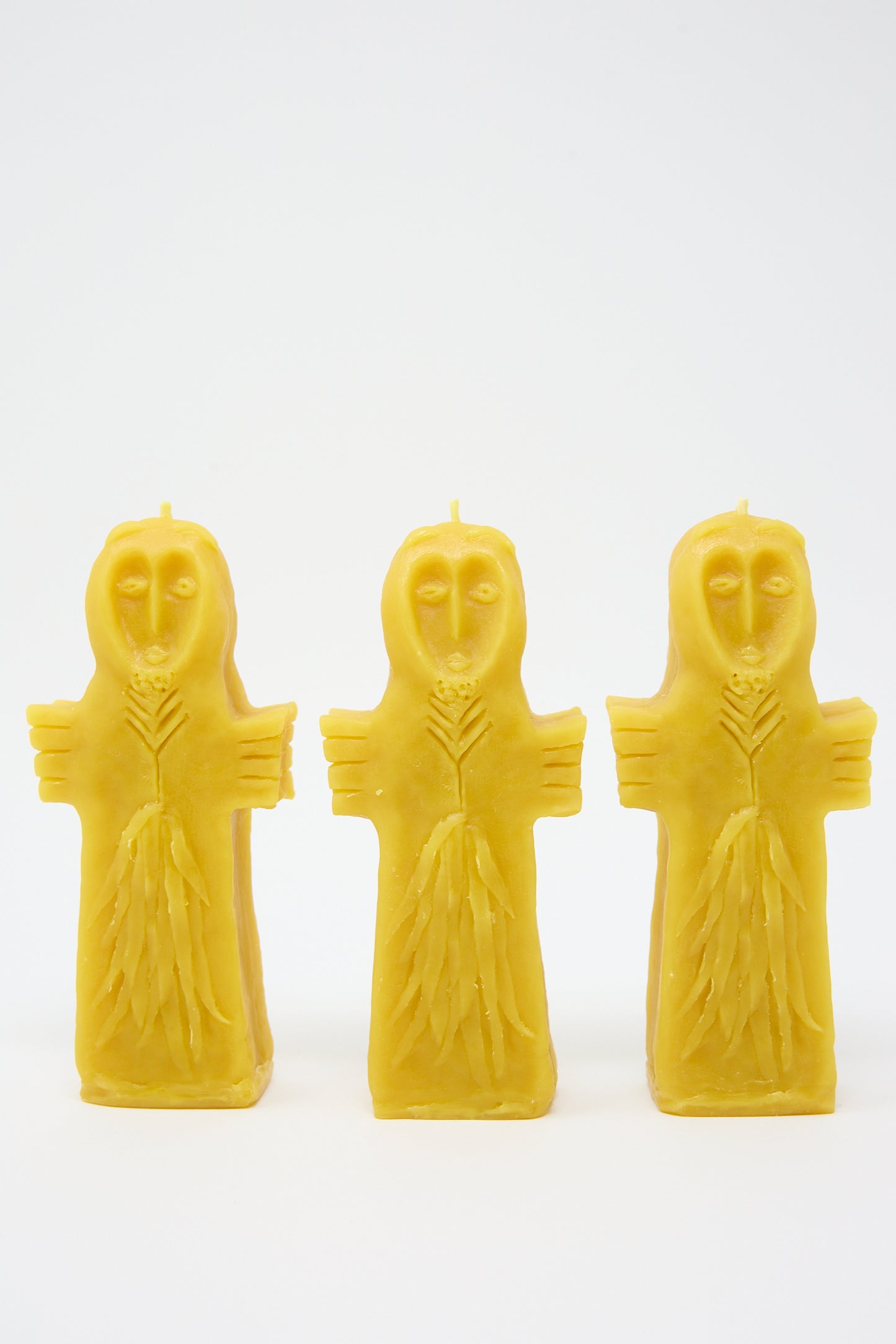 Three yellow Sky Goddess Candles from Rinn to Hitsuji, shaped like robed figures with serene expressions, standing upright against a white background.