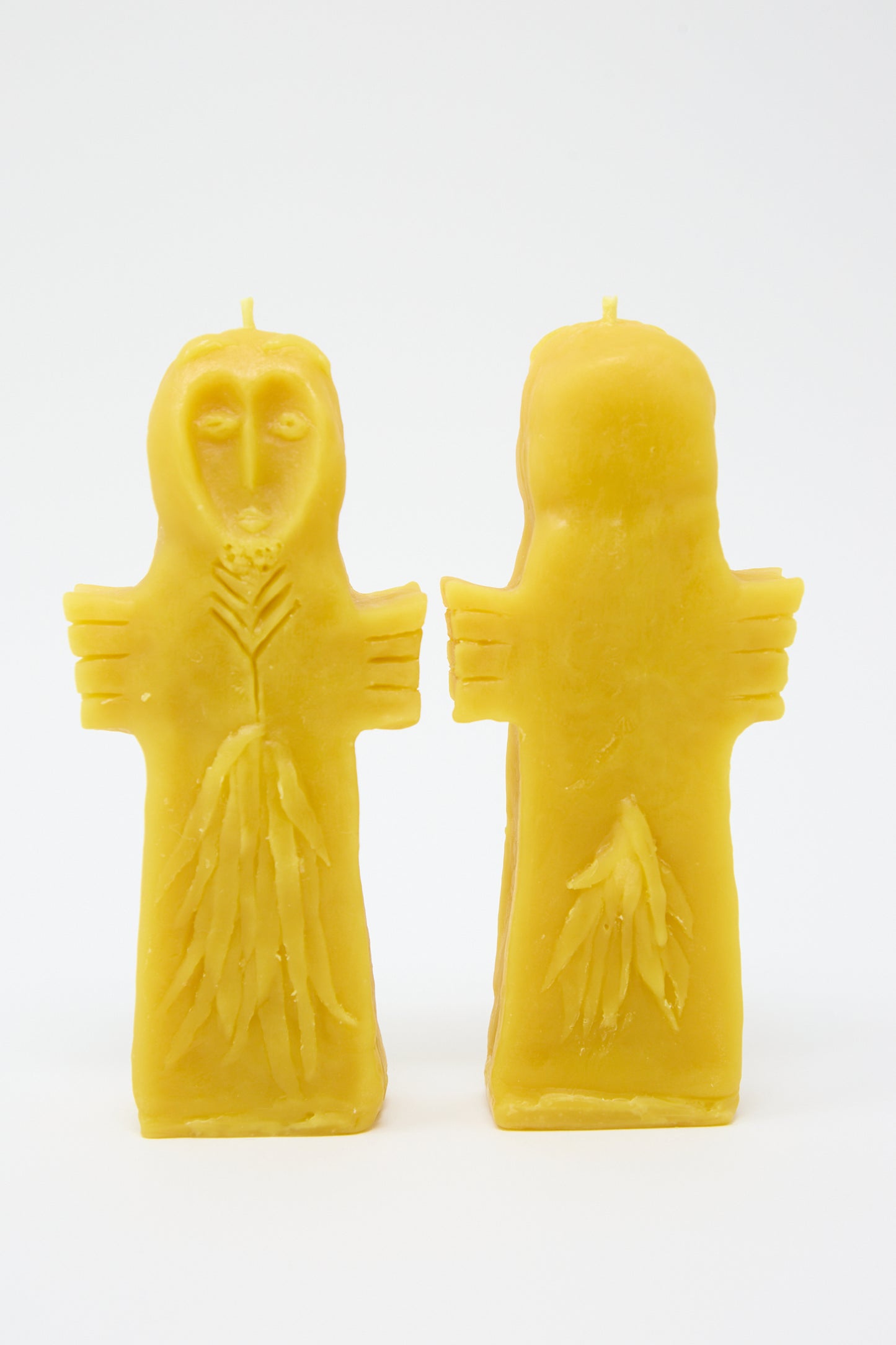 Two yellow Rinn to Hitsuji Sky Goddess Candles shaped like figures with outstretched arms, one resembling an owl and the other featureless, on a white background.