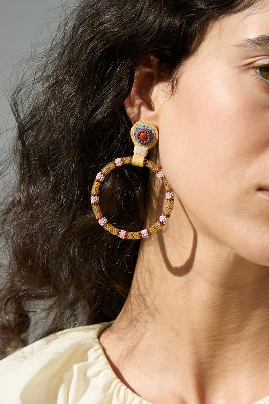 A close up of a woman's Robin Mollicone Large Beaded Hoops in Red Jasper Stones.