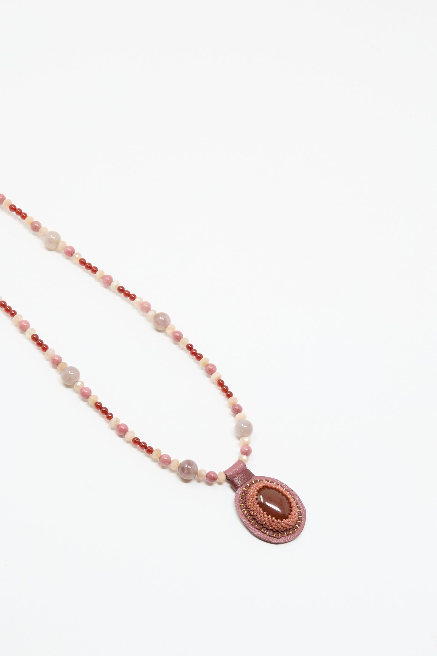 The Love Bead Necklace in Pink by Robin Mollicone features pink, red, and beige vintage glass beads and an oval carnelian charm pendant on a white background.