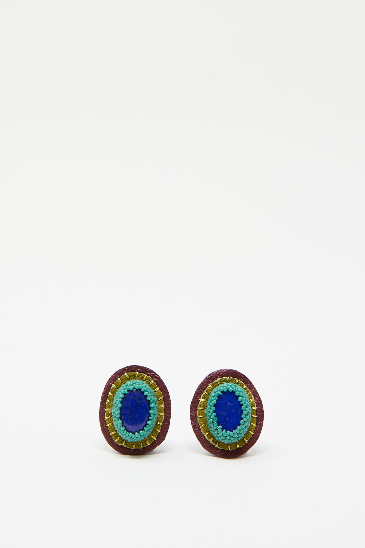 Introducing the Oval Earrings in Lapis by Robin Mollicone, handmade jewelry showcasing a blend of blue, green, and brown layered designs against a white base.
