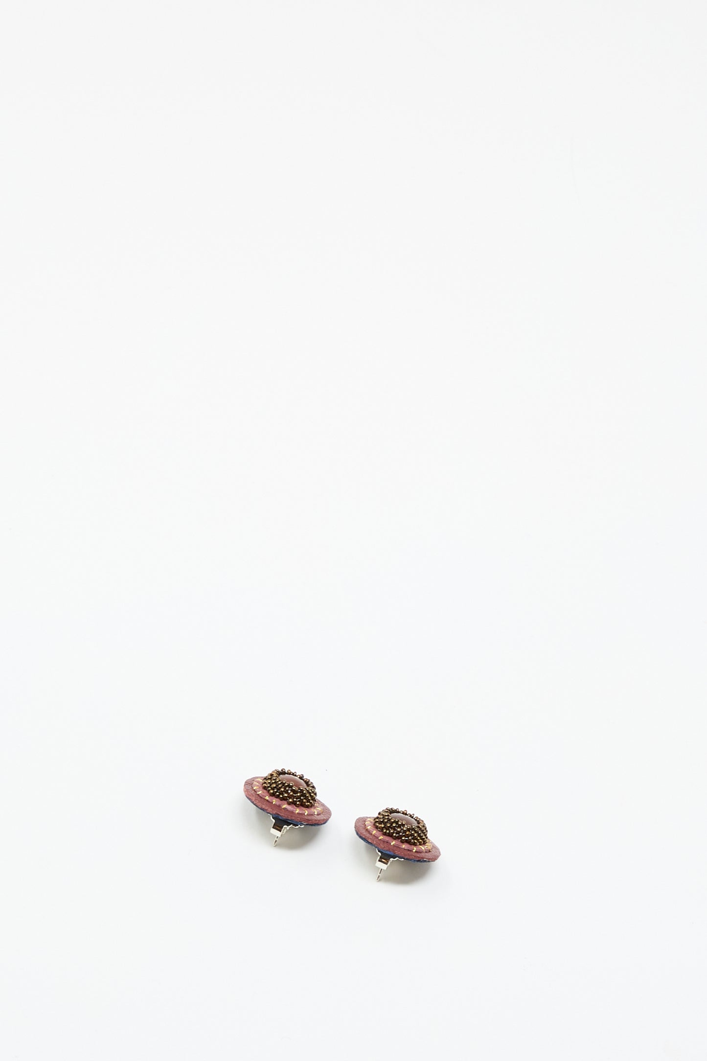 The Robin Mollicone Stud Earrings in Pink with Carnelian feature small, planet-inspired designs with pink rings and dark carnelian centers, shown against a plain white background.