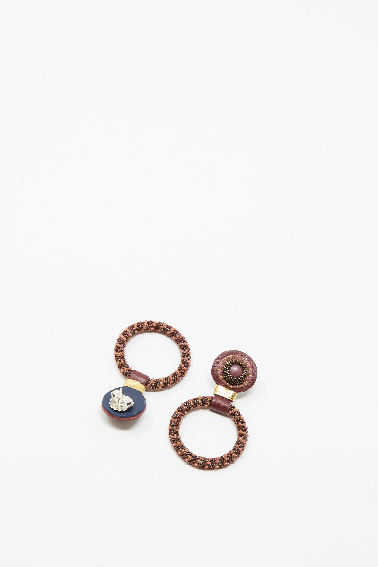 The Small Beaded Hoops in Pink with Rhodonite by Robin Mollicone are handcrafted earrings featuring circular, woven designs in pink tones and rhodonite accents.
