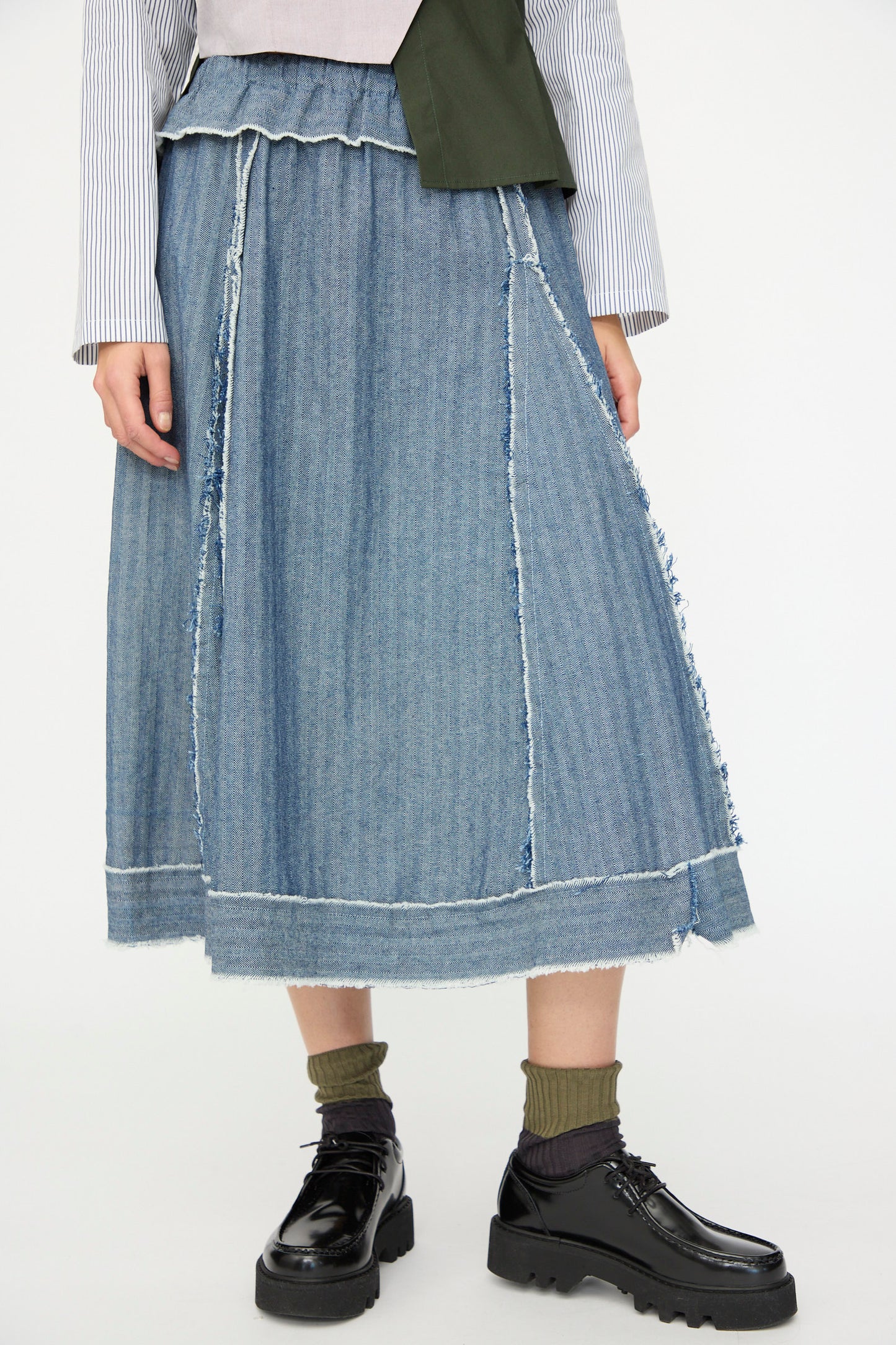 A person wears the SC103 Denim Radio Skirt in Herringbone, styled with green socks and black chunky shoes; only the lower body is fully visible.