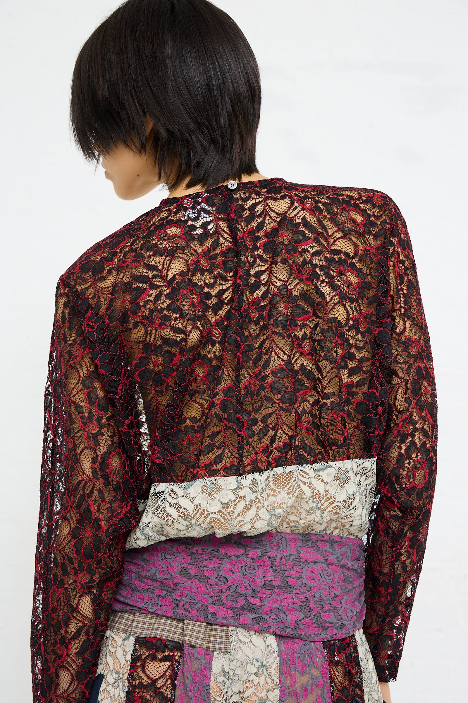 A person seen from the back wearing a SC103 Lace Ritual Top in Thrash with a patchwork skirt.