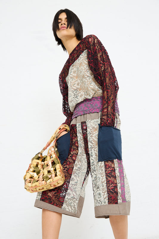 A woman posing in a colorful patchwork ensemble with an oversized SC103 Leather Links Tote in Dew.