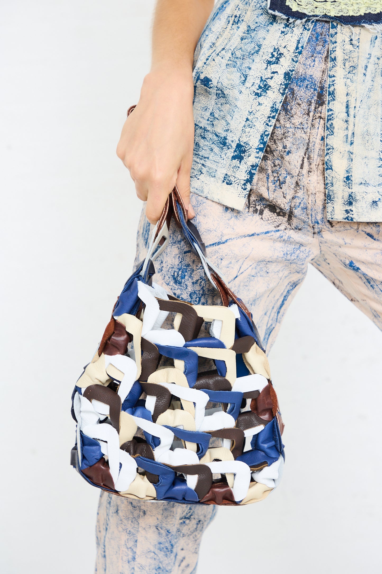 A person holding a blue and white Leather Links Tote in Quill with brown accents by SC103.