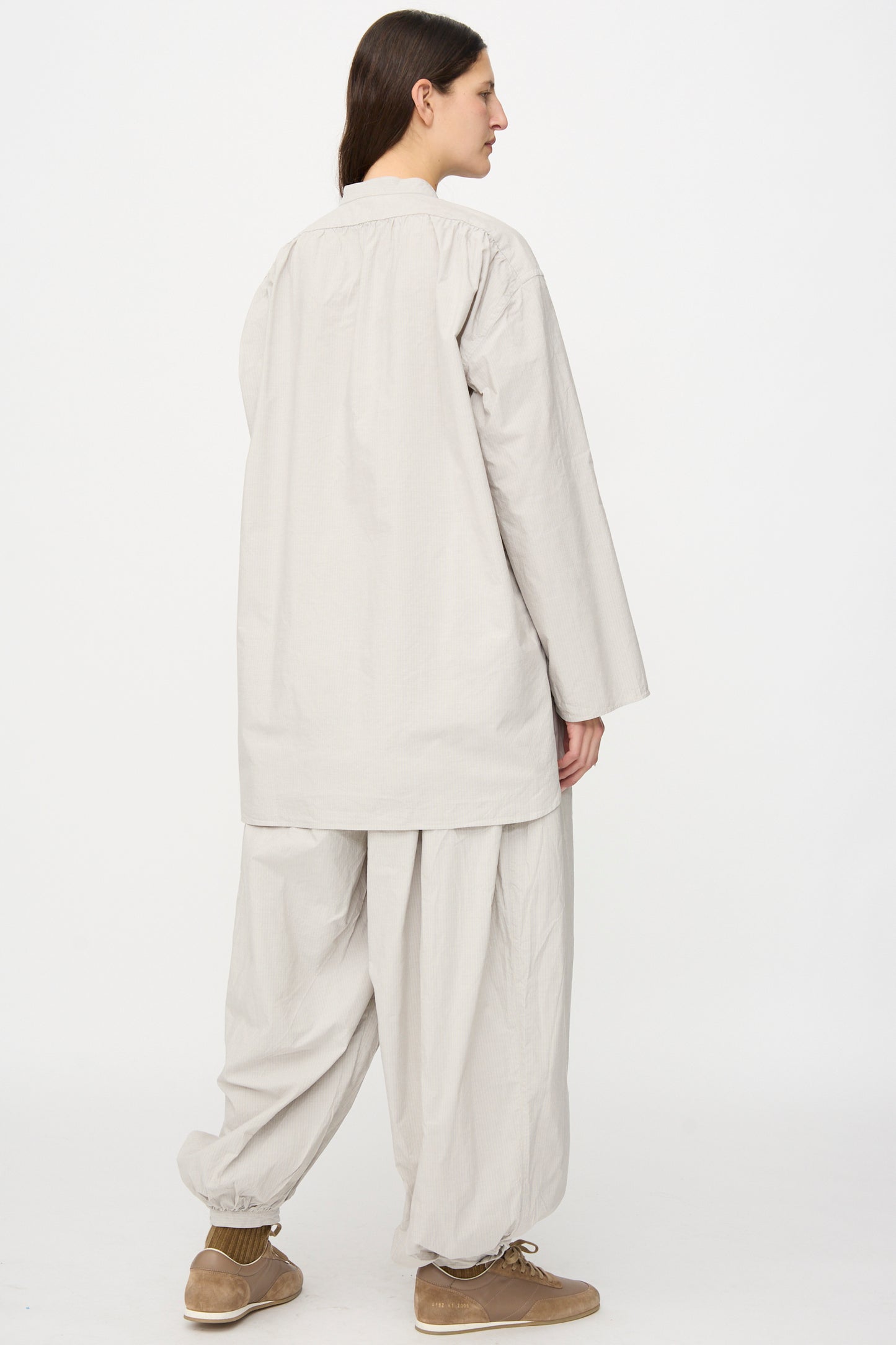 A person faces away, wearing the SONO Shaman Shirt in Dusty Fine Stripe with matching wide pants and brown shoes, standing against a plain white background.