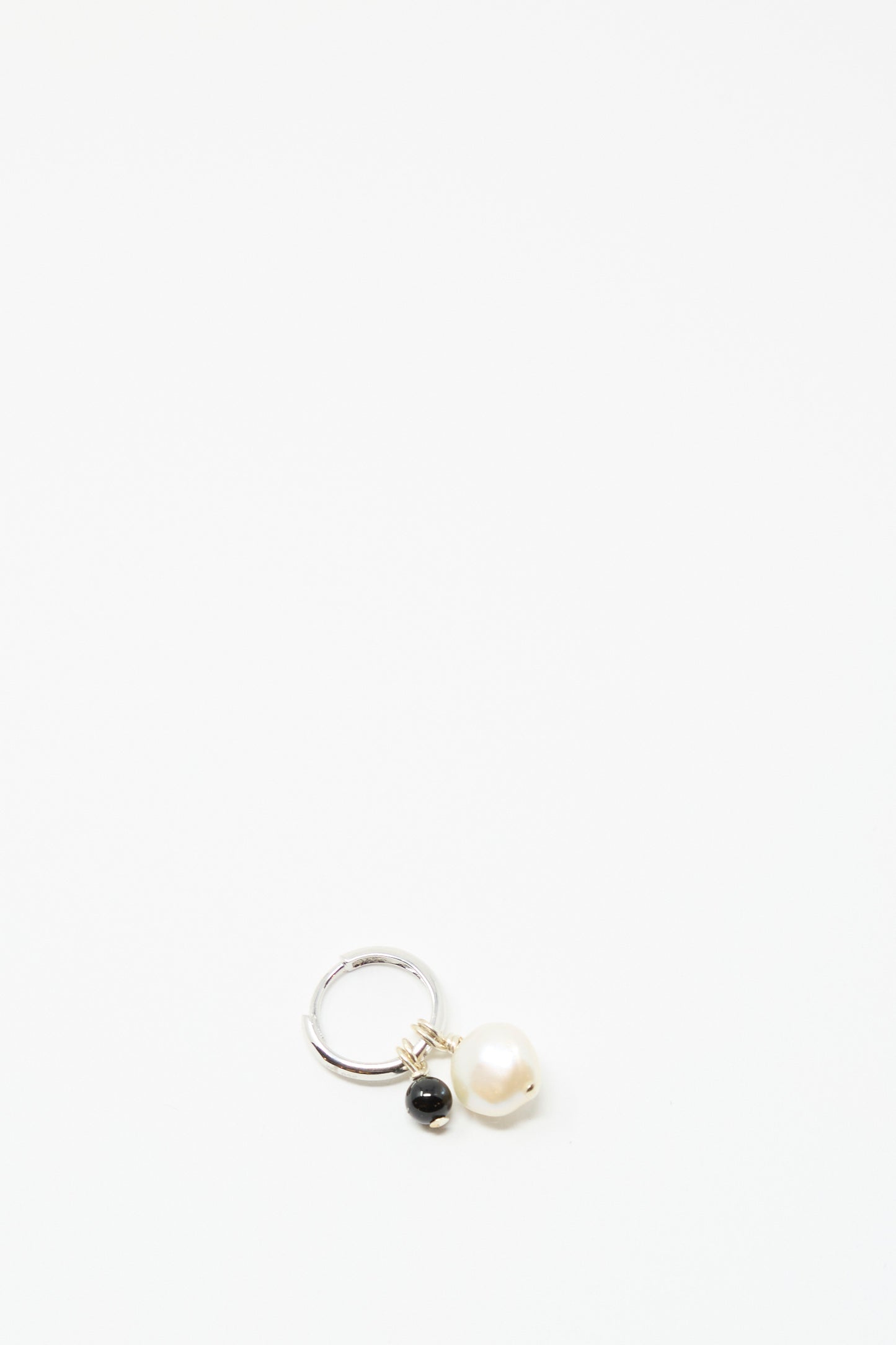 The Santangelo Baba Earring in Baby Black Agate, handcrafted in NYC, features a white pearl and a small black agate stone, shown against a plain white background.